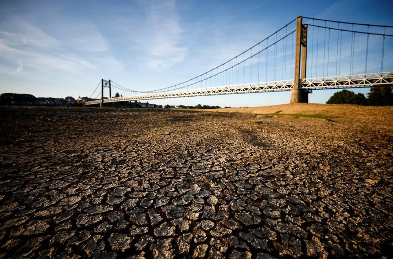 Cracked and dry earth is seen in the wide riverbed of the Loire River near the Anjou-Bretagne bridge as a heatwave hits Europe, in Ancenis-Saint-Gereon, France, June 13, 2022. (Reuters)
