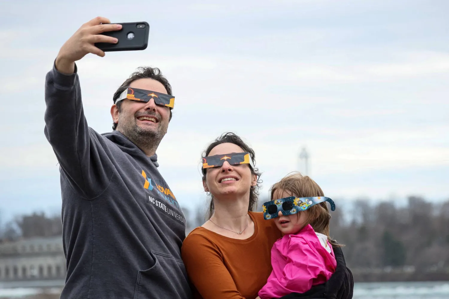 مواطنون يلتقطون «السيلفي» مع اقتراب كسوف للشمس في شلالات نياجرا (رويترز)