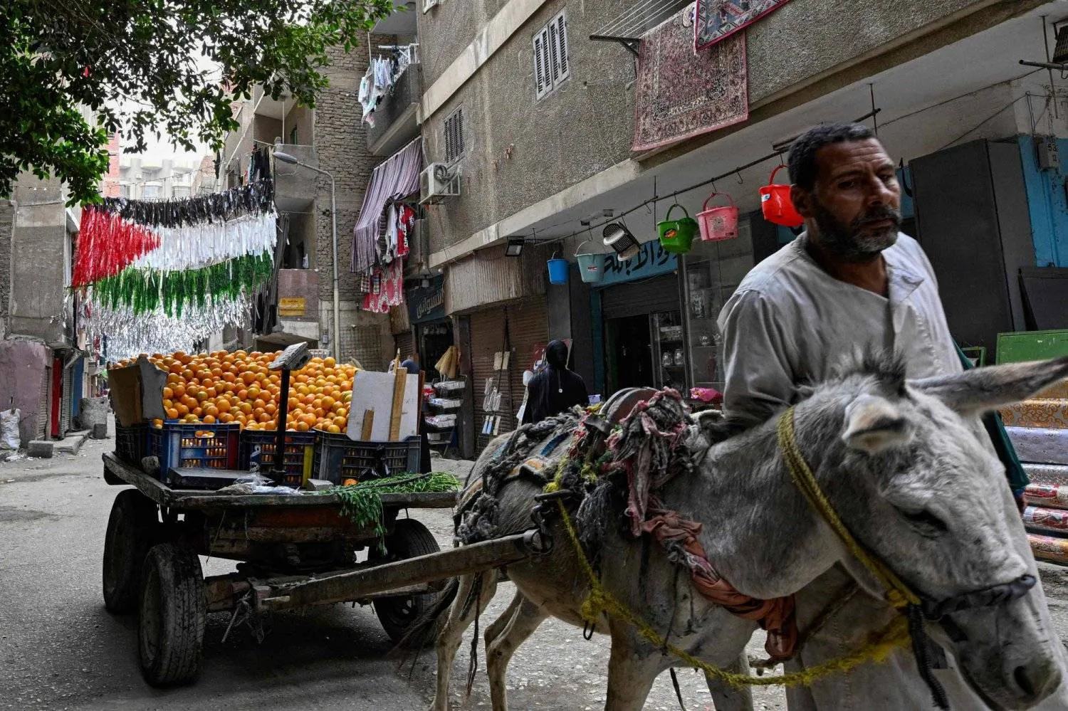 Pedestrians crossing under Ramadan decorations shaped like the Palestinian flag on one of the streets of Giza Governorate in Egypt (AFP)