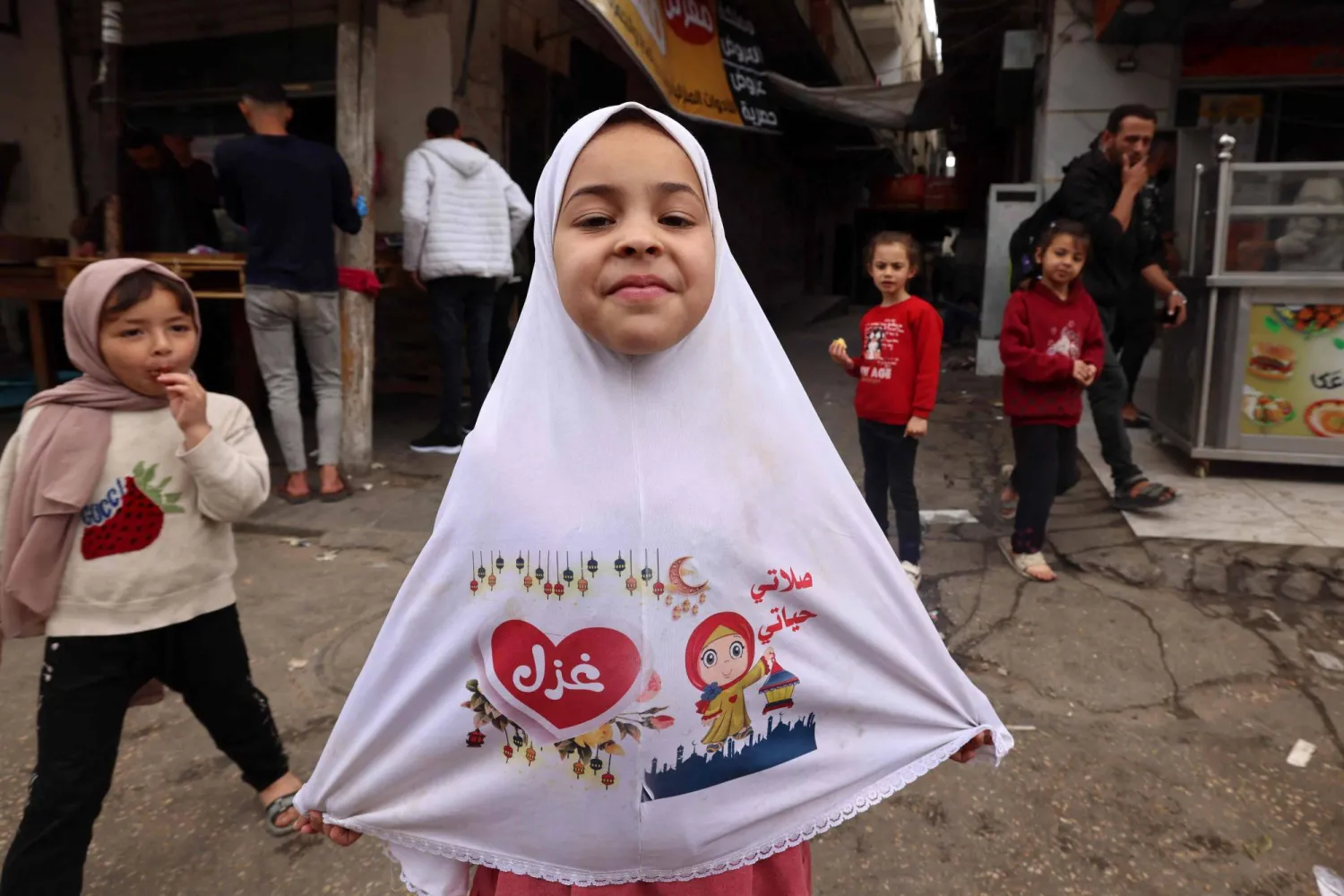 طفلة فلسطينية نازحة سعيدة بمشترياتها الجديدة (أ.ف.ب)