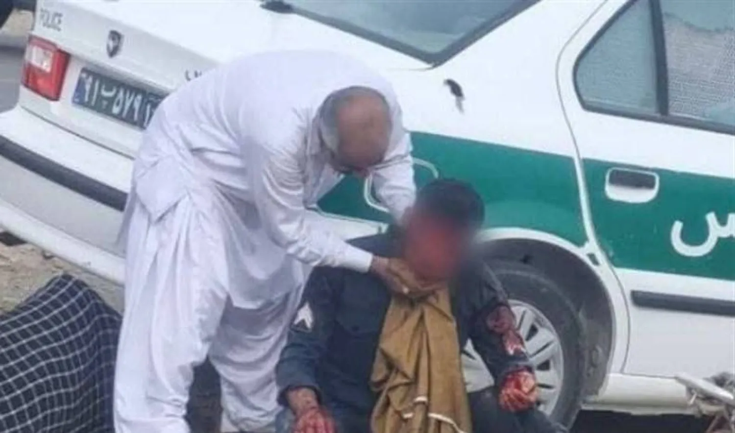 رجل يسعف شرطياً جريحاً في هجوم بلوشستان جنوب شرقي إيران اليوم (تسنيم)