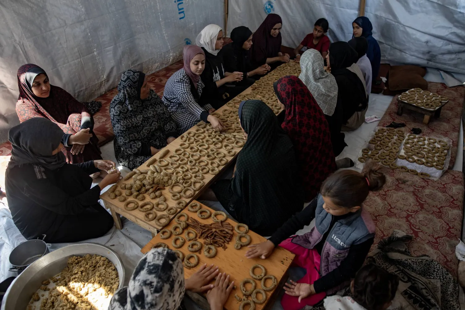 نازحات يعدن كعك العيد داخل خيمة في رفح جنوب قطاع غزة أمس (إ.ب.أ)