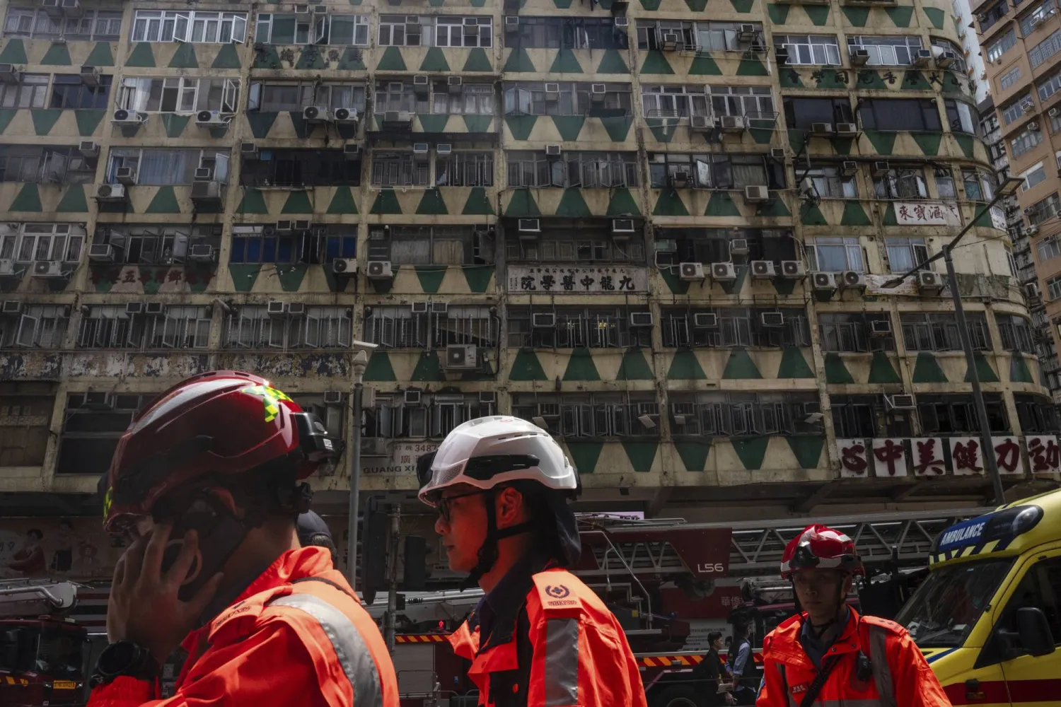Ambulance workers walk past a building called New Lucky House where a fire started in Hong Kong, Wednesday, April 10, 2024. (AP Photo/Louise Delmotte)