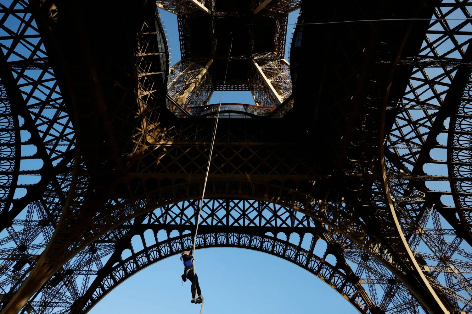 Athlete and Olympics torch bearer Anouk Garnier climbs a 110-meter-long rope launched in the center of the Eiffel Tower square to reach the 2nd floor and to attempt to break the world record for rope climbing, in Paris, France, April 10, 2024. REUTERS/Sarah Meyssonnier