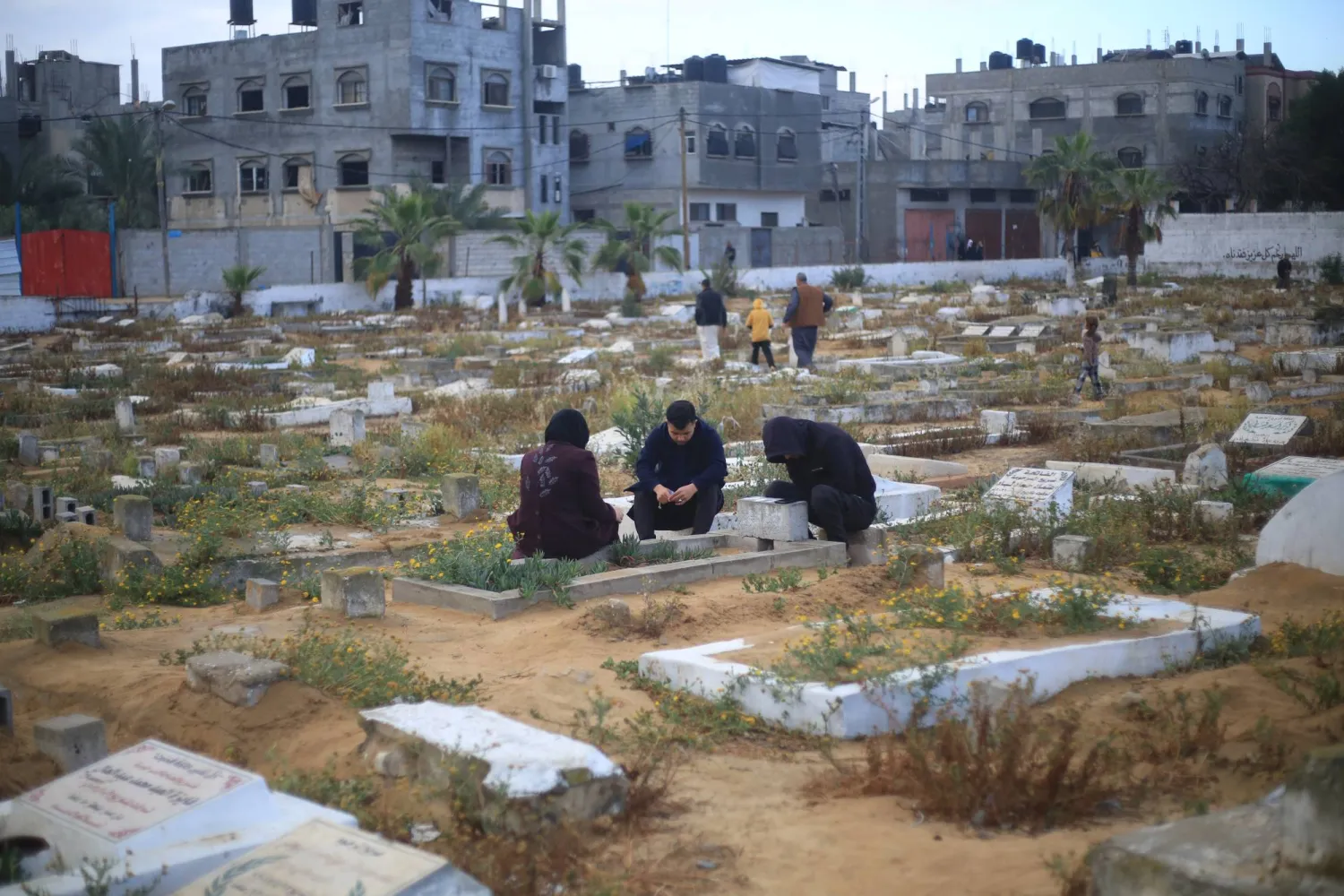 أشخاص يزورون قبر أحد أحبائهم خلال عيد الفطر في رفح جنوب قطاع غزة 10 أبريل 2024 (د.ب.أ)