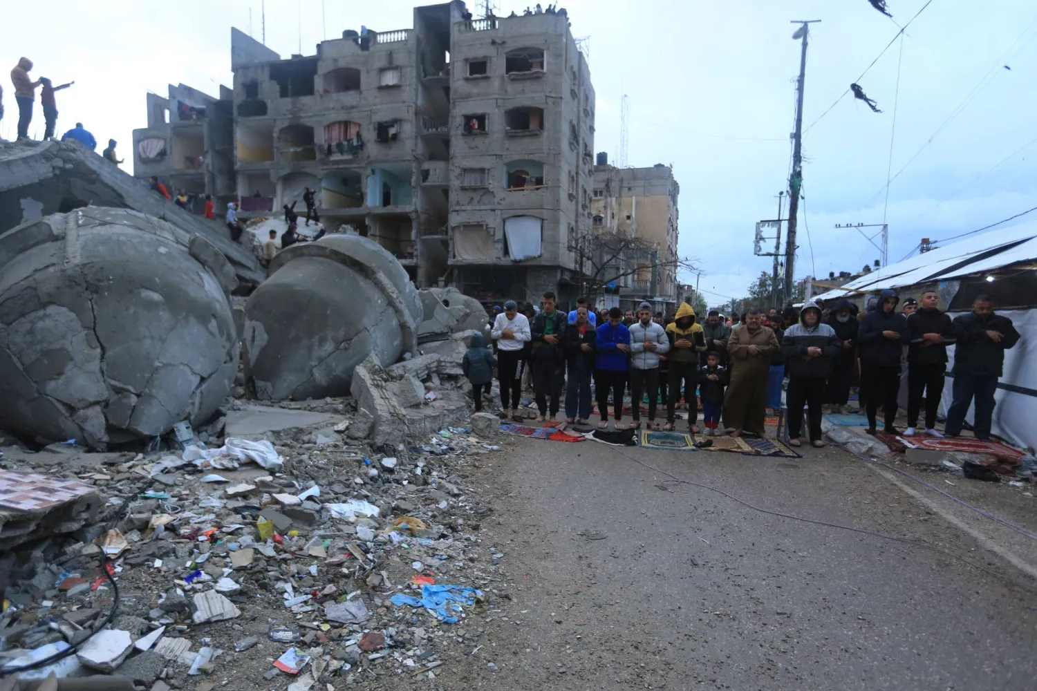 مسلمون يؤدون صلاة عيد الفطر أمام مسجد الفاروق المدمر في رفح جنوب قطاع غزة 10 أبريل 2024 (د.ب.أ)