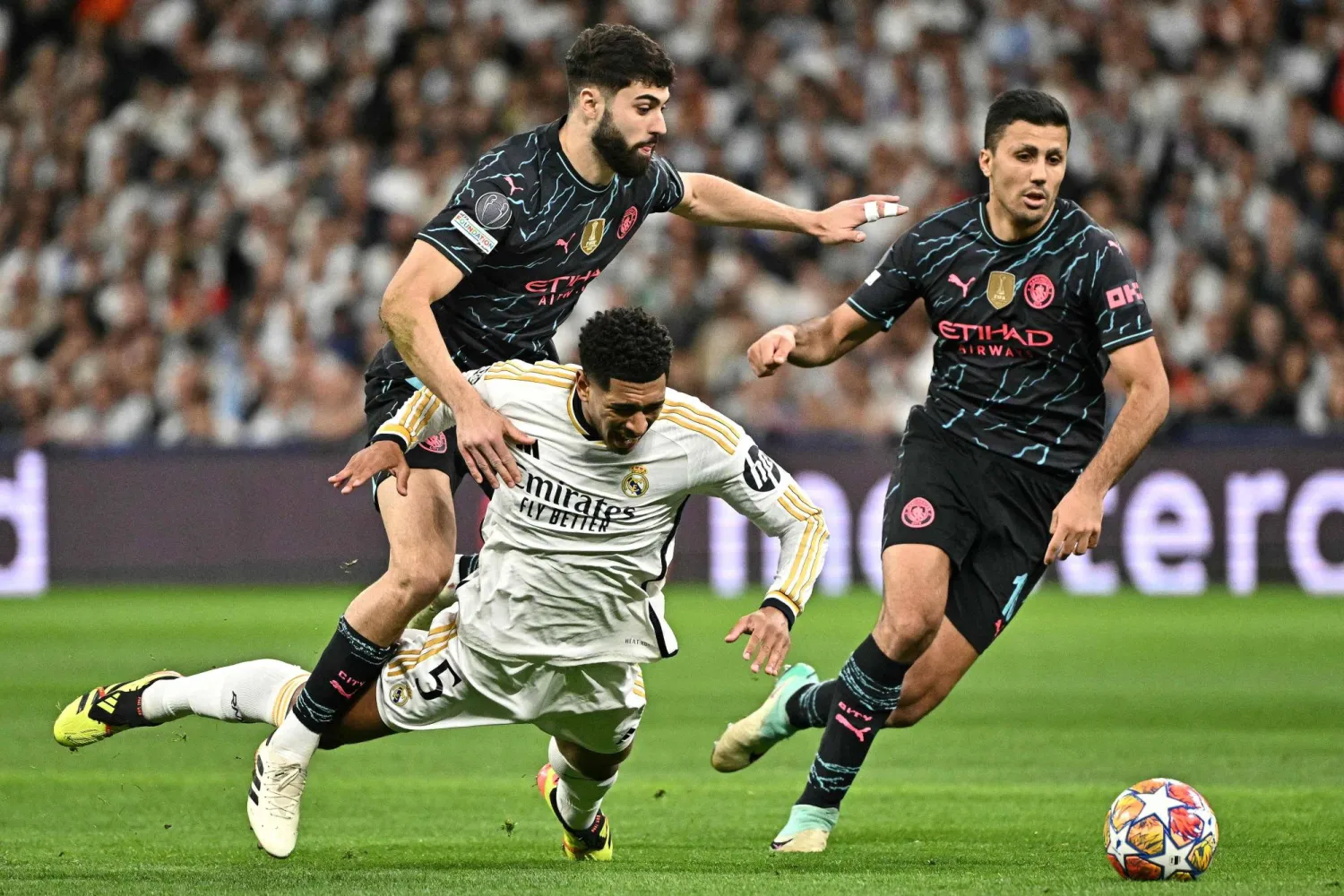 رودري يحاول اللحاق بالكرة من أمام بيلينغهام في قمة العملاقين الثلاثاء (أ.ف.ب)