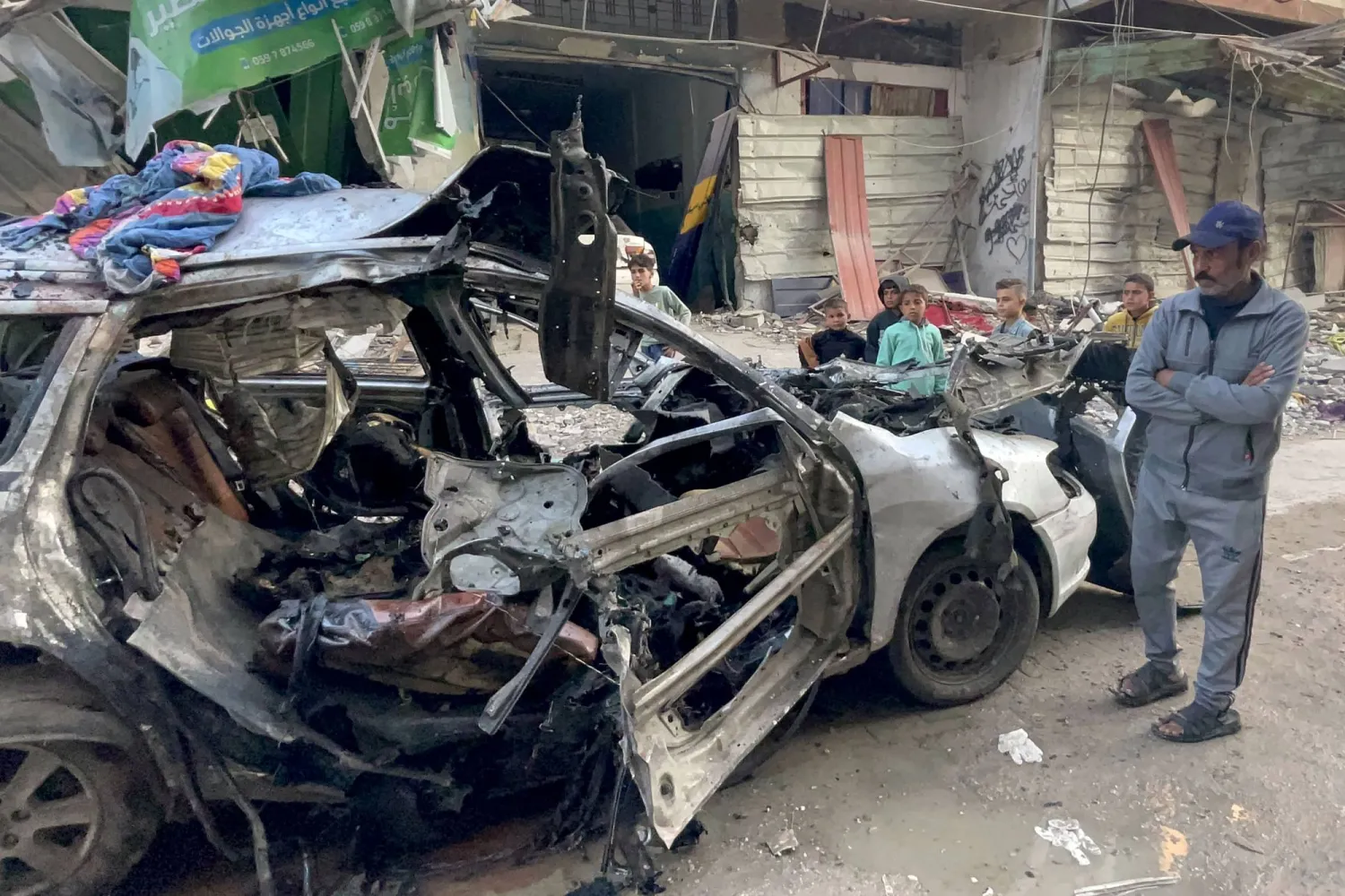Onlookers check the car in which three sons of Hamas leader Ismail Haniyeh were reportedly killed in an Israeli air strike in al-Shati camp, west of Gaza City on April 10, 2024, amid the ongoing conflict between Israel and the Palestinian Hamas group. (Photo by AFP)