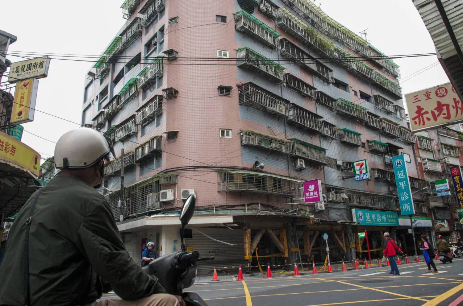 A motorcyclist looks at a tilted building caused by the April 3 magnitude-7.4 earthquake at Tucheng district in New Taipei City on April 6, 2024. (Photo by Sam Yeh / AFP)