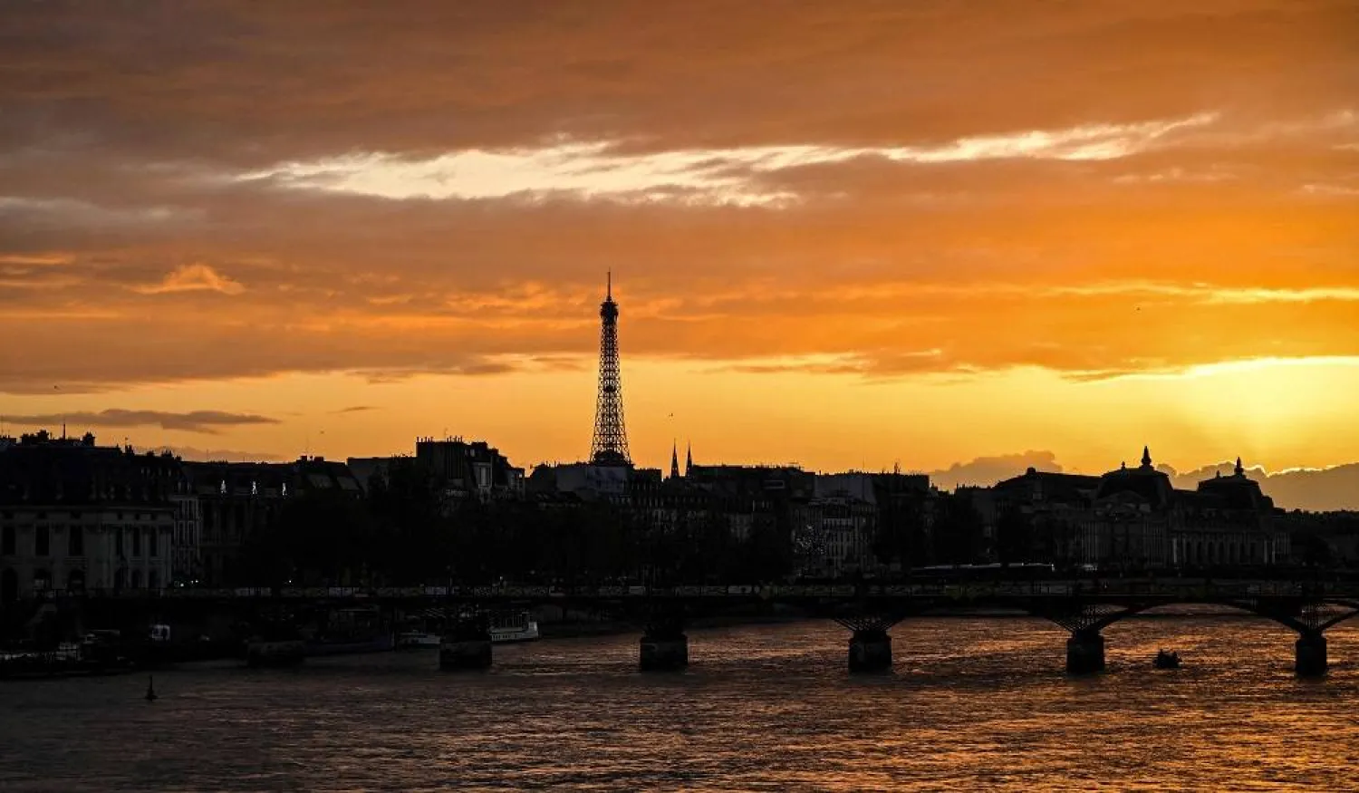 This photograph taken on April 9, 2024 shows the sun going down above the Eiffel Tower and the Seine river in Paris. (AFP)