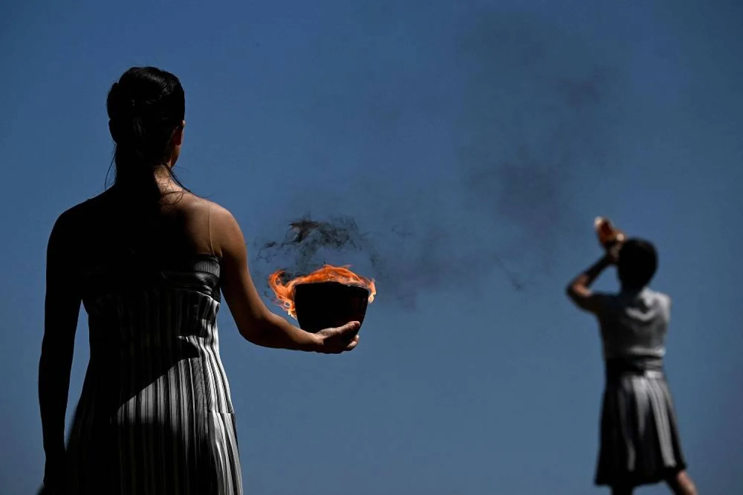 A woman in the role of a priestess holds the Olympic flame after lighting it during the rehearsal of the flame lighting ceremony for the Paris 2024 Olympics Games at the ancient temple of Hera on the Olympia archeological site, birthplace of the ancient Olympics in southern Greece, on April 15, 2024. (AFP)