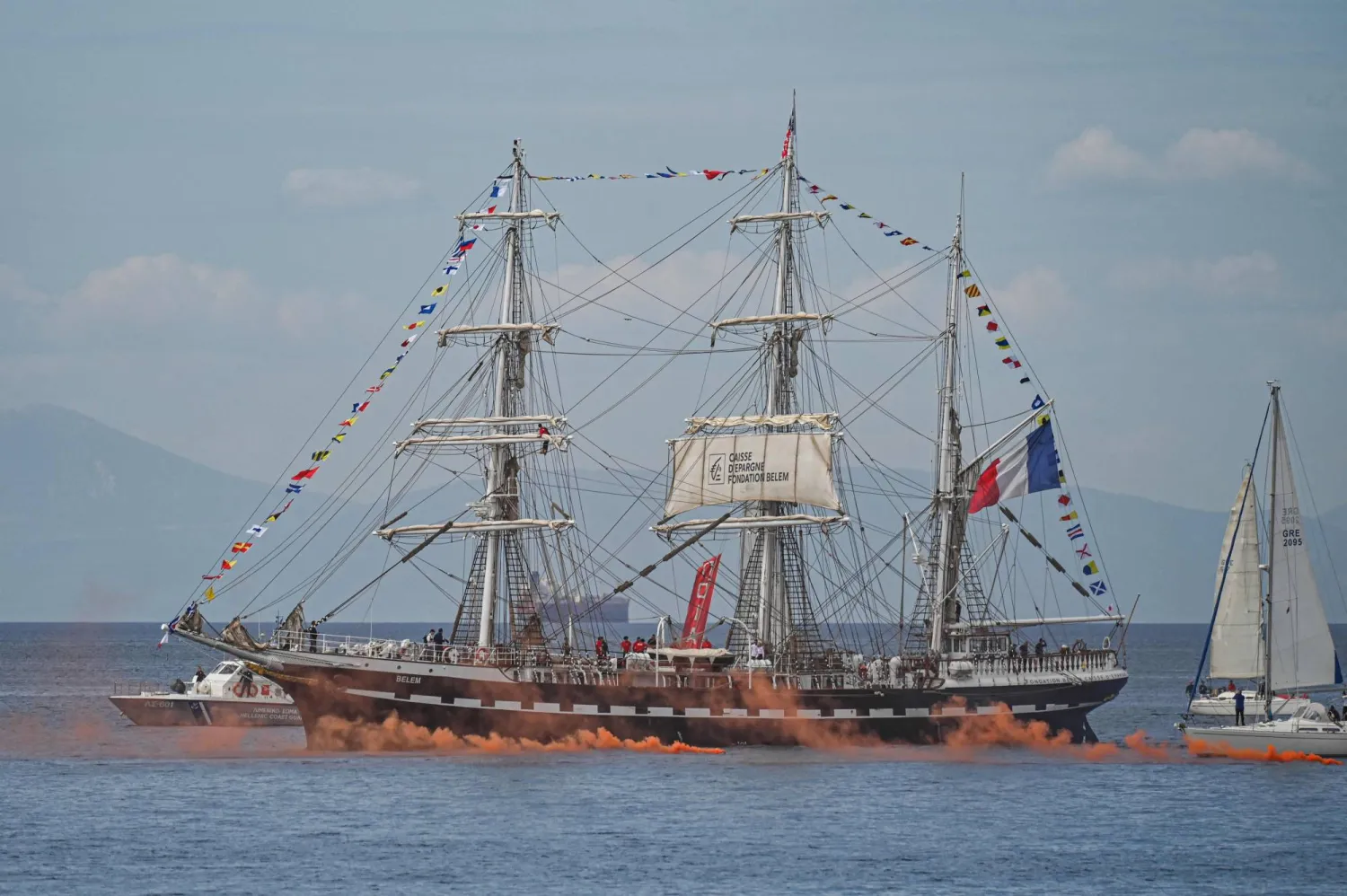 French 19th-century three-masted barque Belem, escorted by sailboats, sails after leaving the Piraeus port, near Athens, with the Olympic flame on board to begin its journey to France on April 27, 2024. (Photo by Theophile Bloudanis / AFP)