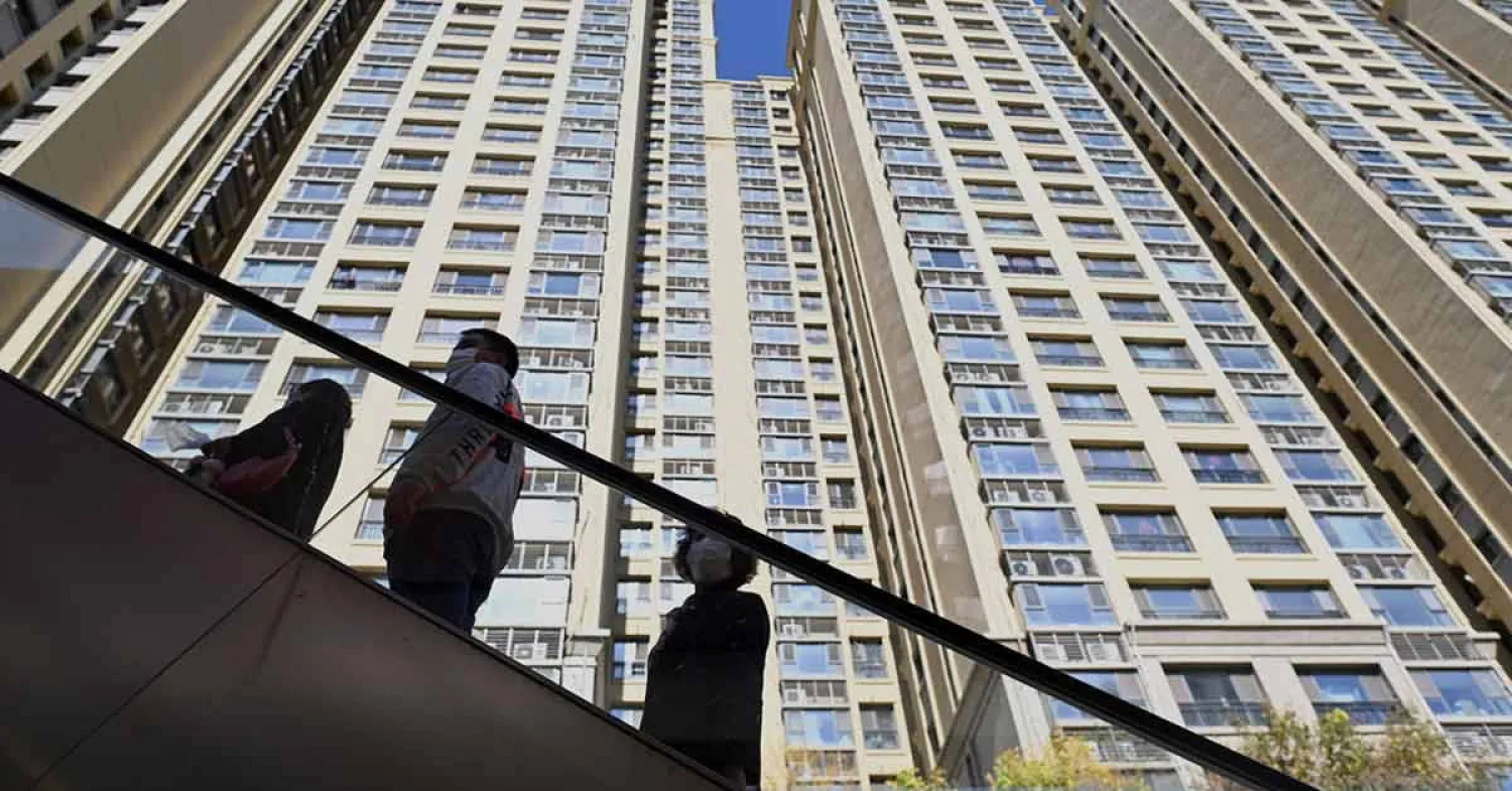 صينيون على أحد الجسور وسط حي سكني بالعاصمة بكين (أ.ف.ب)