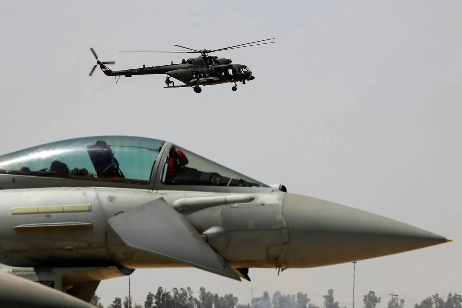 مروحية عسكرية تحلّق فوق إحدى الطائرات خلال عرض جوي في قاعدة بلد الجوية شمال بغداد في 24 أبريل 2024 بمناسبة الذكرى 93 لتأسيس القوة الجوية العراقية عام 1931 (أ.ف.ب)