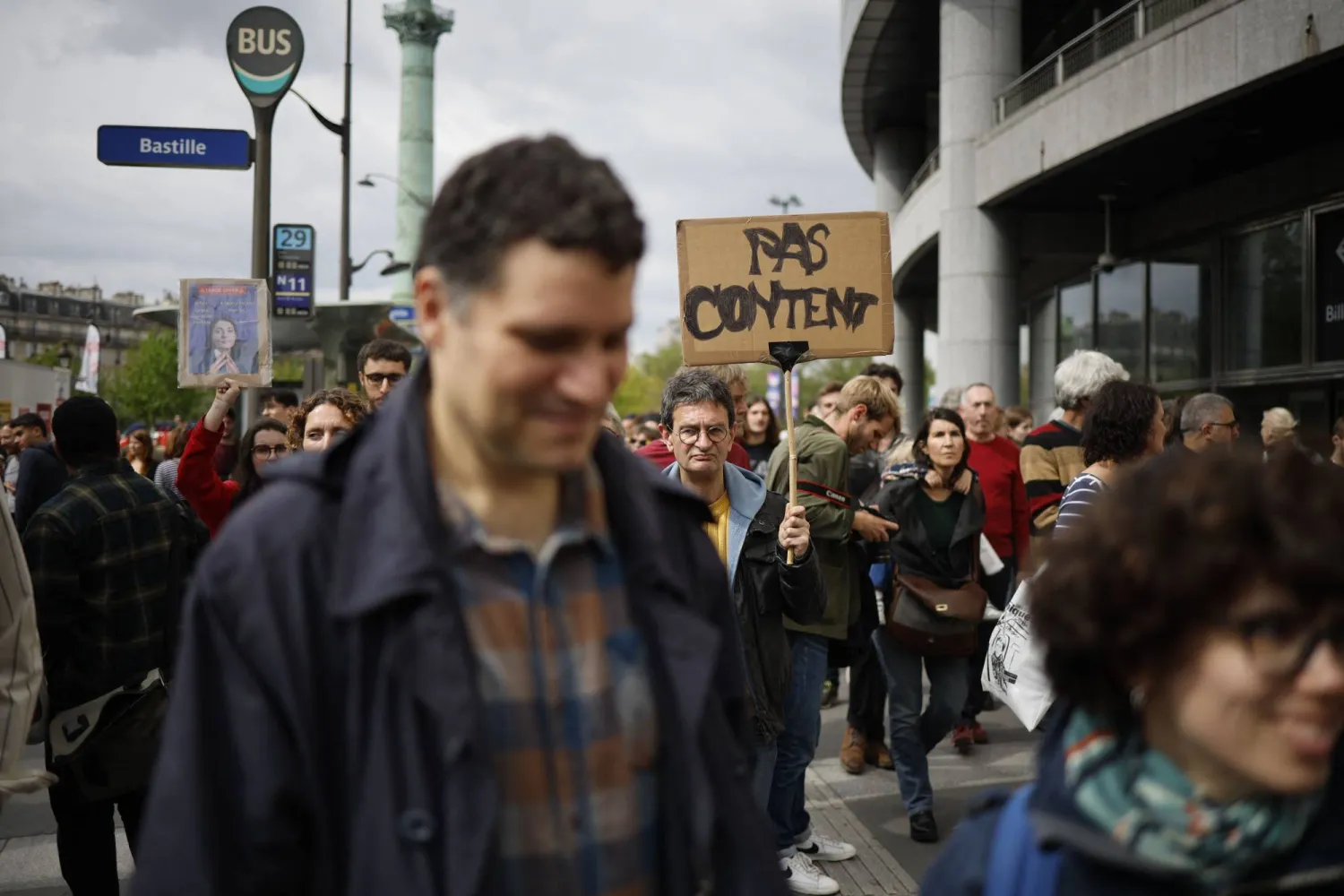 متظاهر يحمل لافتة كتب عليها «لست سعيداً» خلال مسيرة عيد العمال بمناسبة يوم العمال العالمي في باريس (أ.ف.ب)
