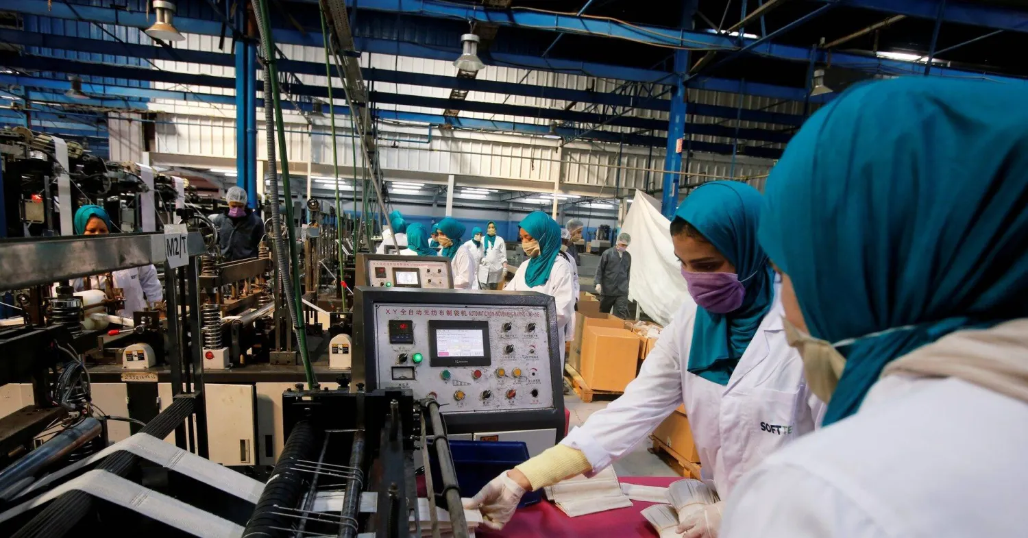 موظفون يجمعون أقنعة الوجه الواقية من خط الإنتاج في أحد المصانع في الدار البيضاء (رويترز)