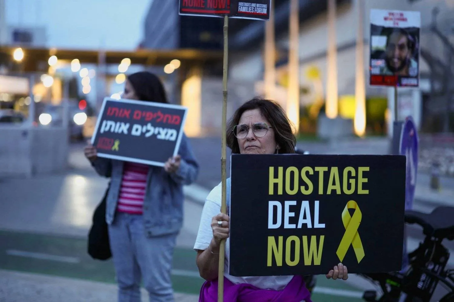 متظاهرة تحمل لافتة في تل أبيب تطالب بإبرام صفقة لتحرير المحتجزين في غزة (رويترز)