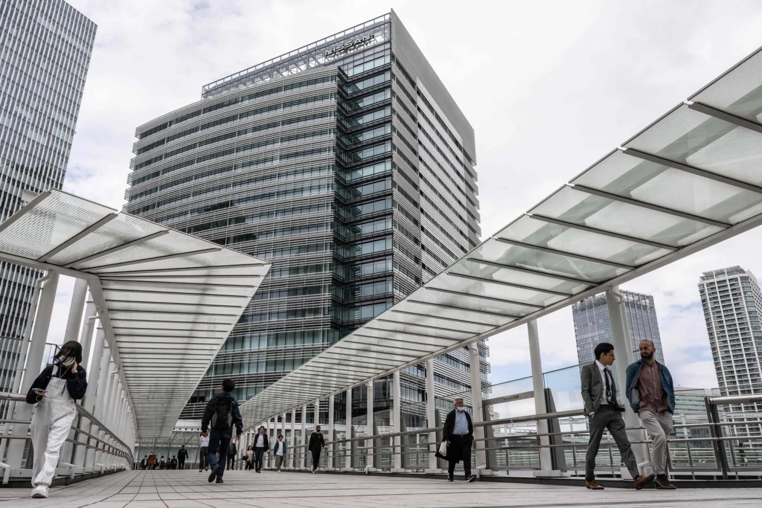 مشاة على جسر في منطقة إدارية بمدينة يوكوهاما اليابانية (أ.ف.ب)