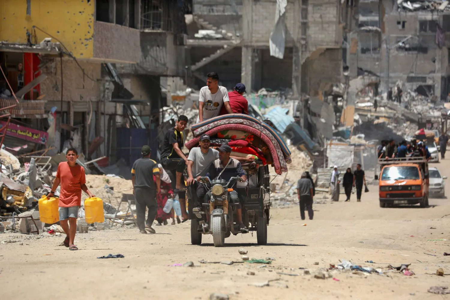 نازحون فلسطينيون وصلوا على دراجة ثلاثية العجلات تحمل أمتعتهم بعد عودتهم إلى حي مدمر في خان يونس جنوب قطاع غزة، 9 مايو 2024 (أ.ف.ب)