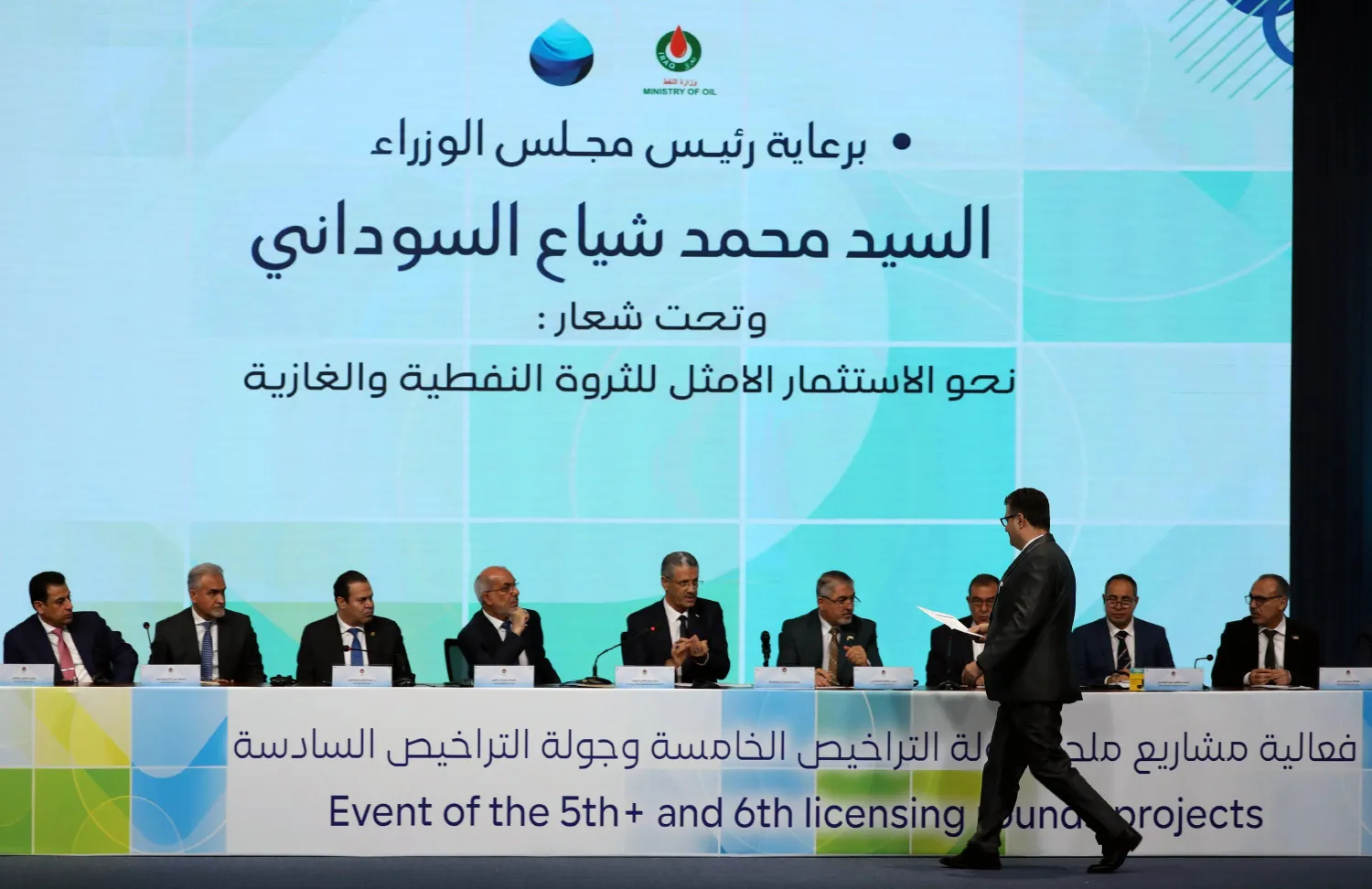 ممثل شركة نفط وغاز أجنبية يسير لتسليم وثائق عقده إلى وزير النفط العراقي حيان عبد الغني خلال حفل جولة التراخيص السادسة لمشاريع النفط والغاز يوم السبت (إ.ب.أ)