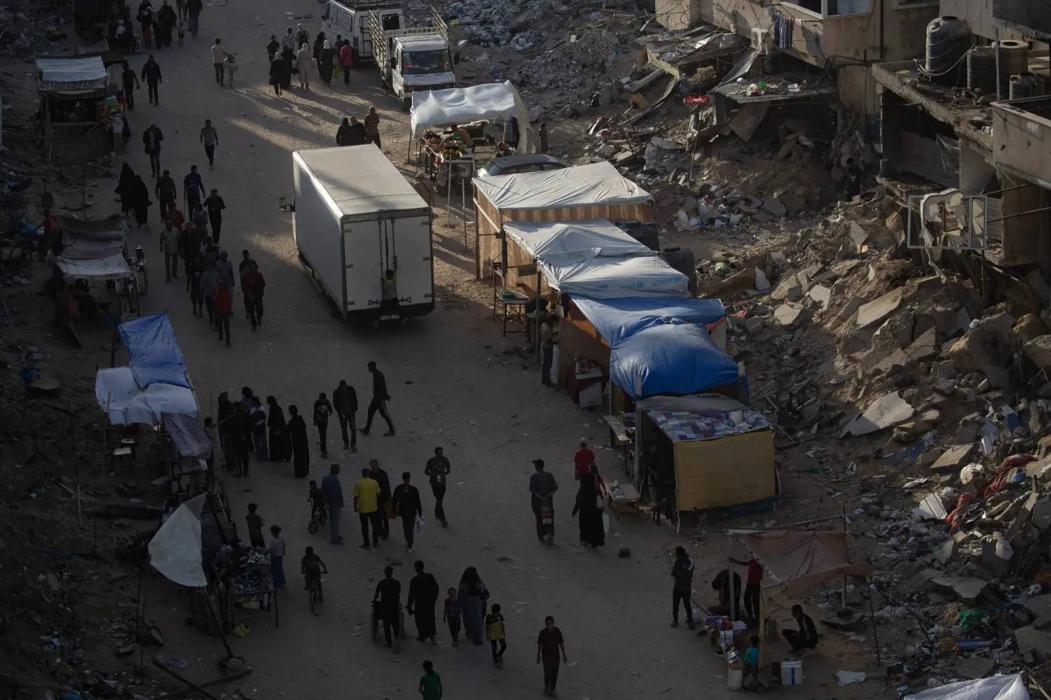 فلسطينيون نازحون من رفح يسيرون في مخيم بخان يونس (إ.ب.أ)