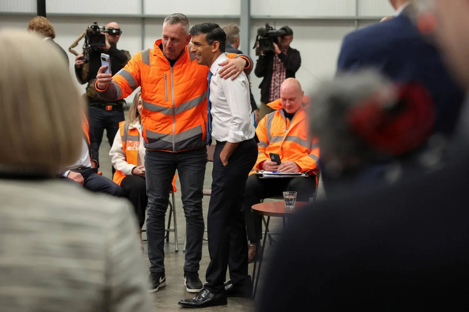 سوناك يلتقط صورة مع أحد الموظفين في مركز توزيع وسائل النقل في إلكستون ببريطانيا (رويترز)