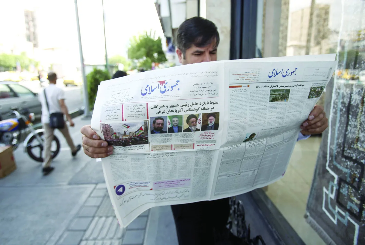 إيراني يقرأ صحيفة «جمهوري إسلامي» غداة تحطم مروحية رئيسي (إ.ب.أ)