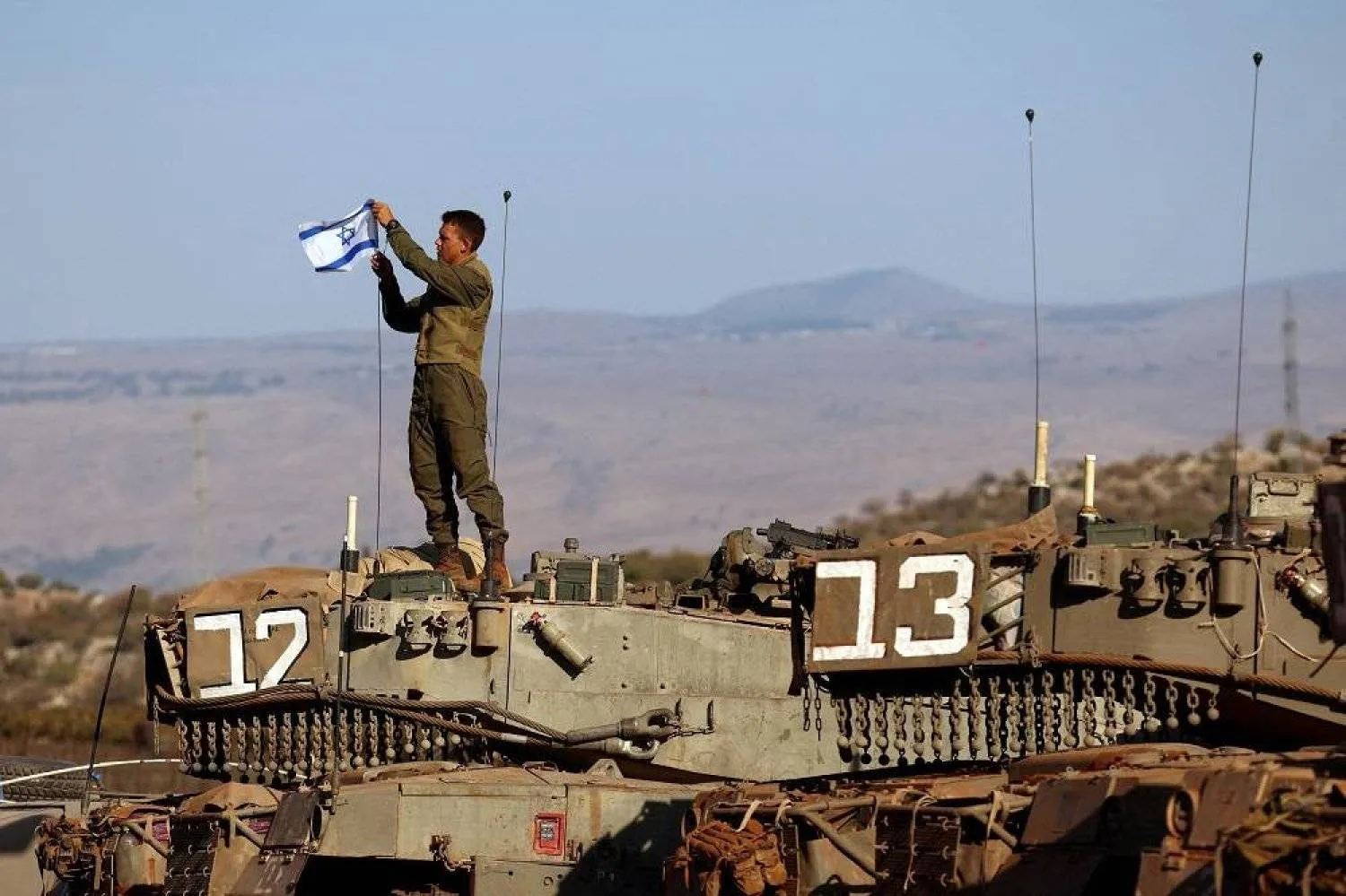 A soldier installs an Israeli flag on a tank during a military drill near Israel's border with Lebanon in northern Israel, October 26, 2023. (Reuters)
