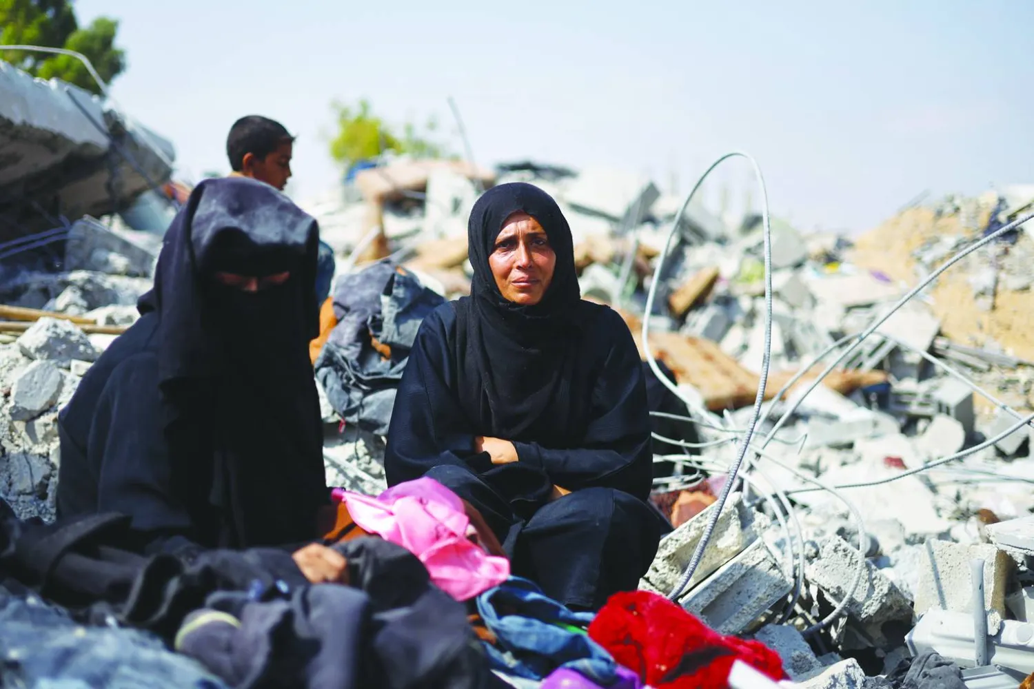 
شقيقتان مصدومتان تبحثان عن أمهما المفقودة تحت أنقاض منزل دمَّرته ضربة إسرائيلية في خان يونس جنوب قطاع غزة أمس (رويترز)