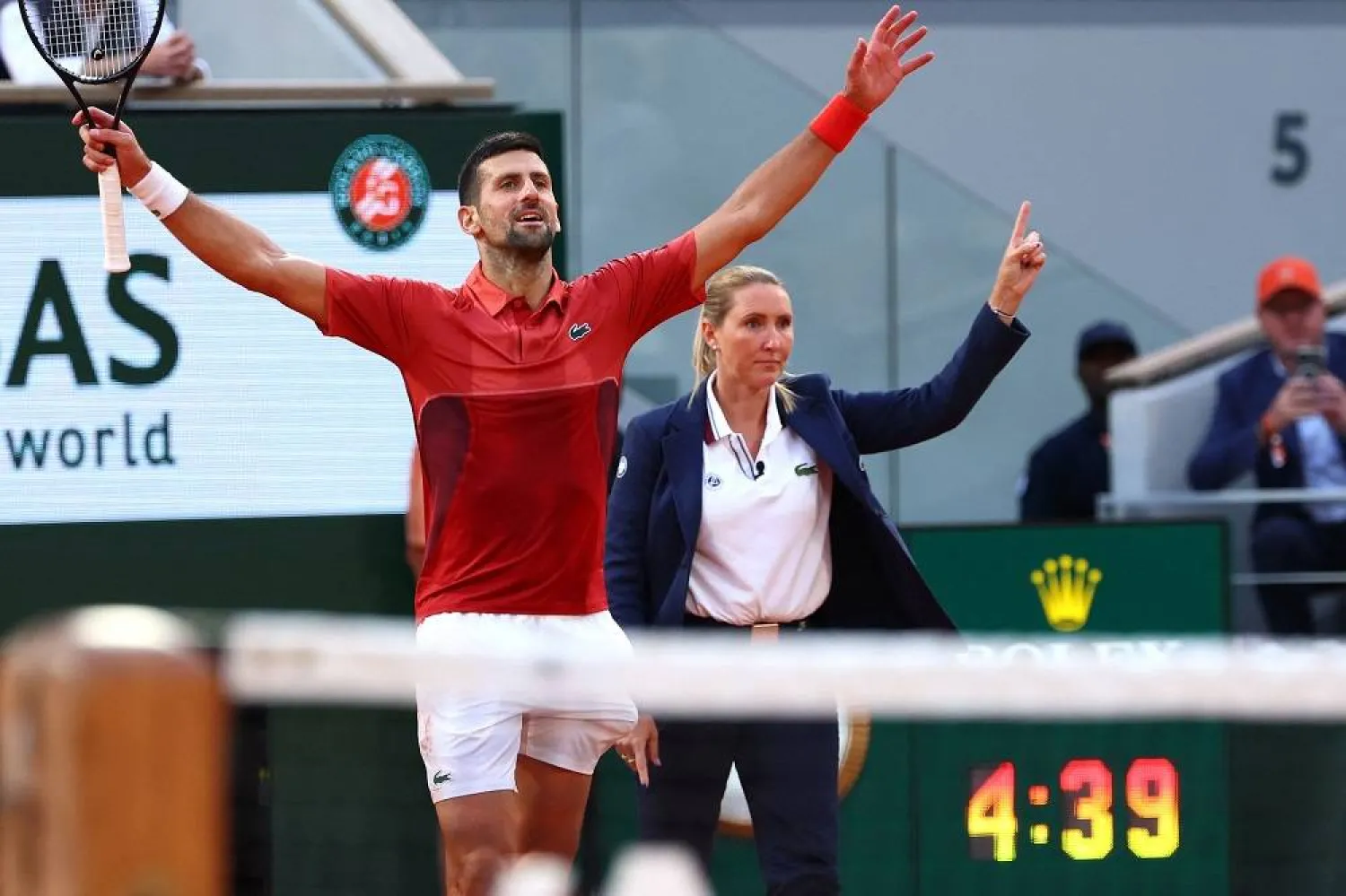 Serbia's Novak Djokovic (L) celebrates next to the umpire and a timer clock reading 4 hours and 39 minutes after winning against Argentina's Francisco Cerundolo at the end of their men's singles round of sixteen match on Court Philippe-Chatrier on day nine of the French Open tennis tournament at the Roland Garros Complex in Paris on June 3, 2024. (AFP)