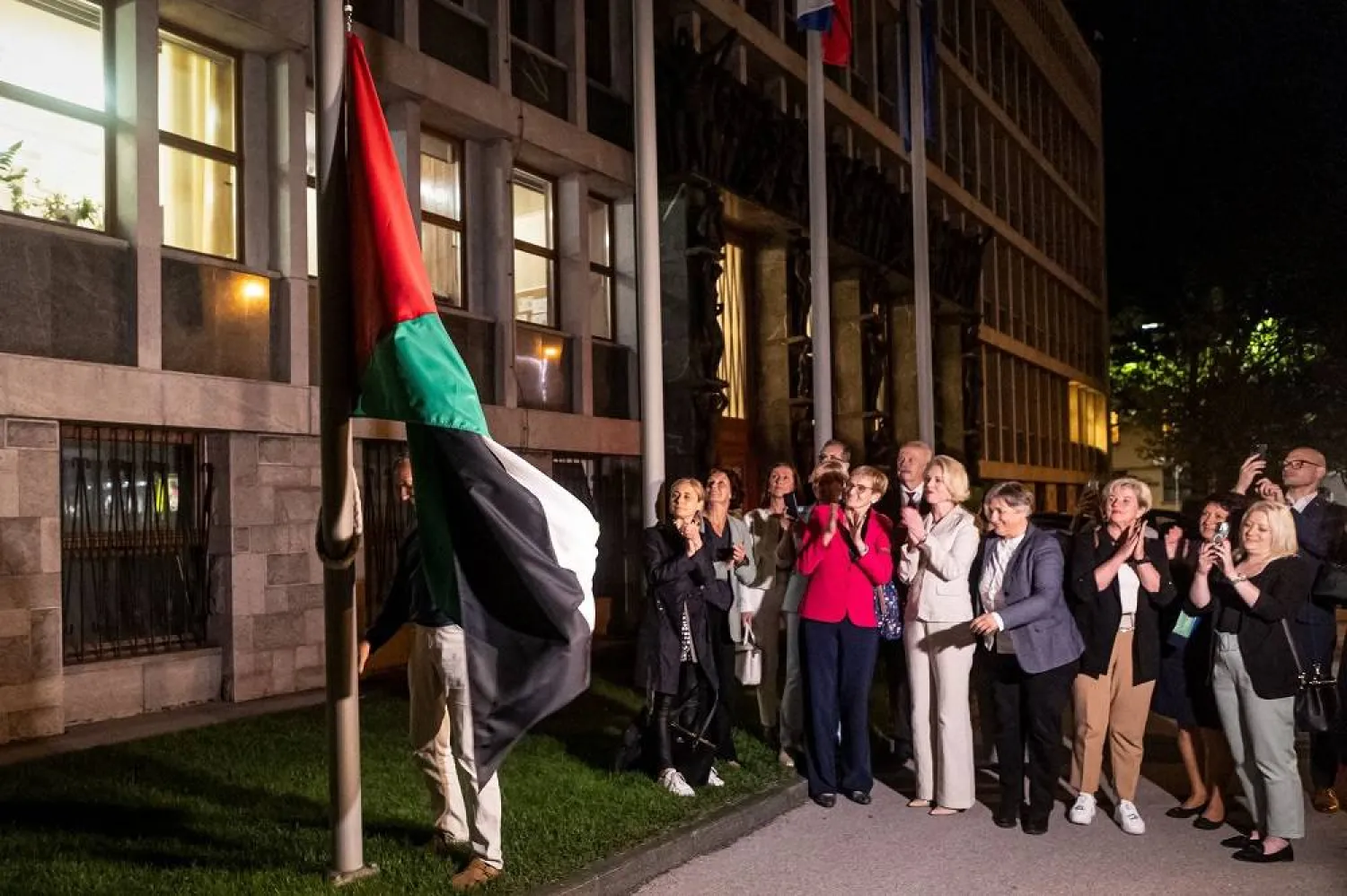 People hang a Palestinian flag in front of the Parliament building after the National Assembly recognized the Palestinian state following a parliamentary vote in Ljubljana, on June 4, 2024. (AFP) 