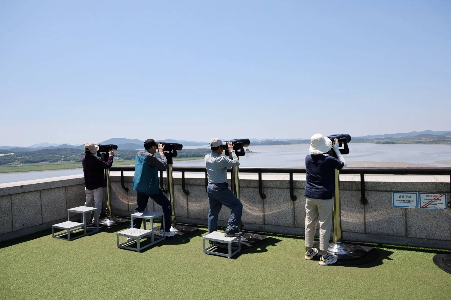 People look towards the north through a pair of binoculars from the observation deck near the demilitarized zone that separates the two Koreas in Paju, South Korea, June 4, 2024. REUTERS/Kim Hong-Ji