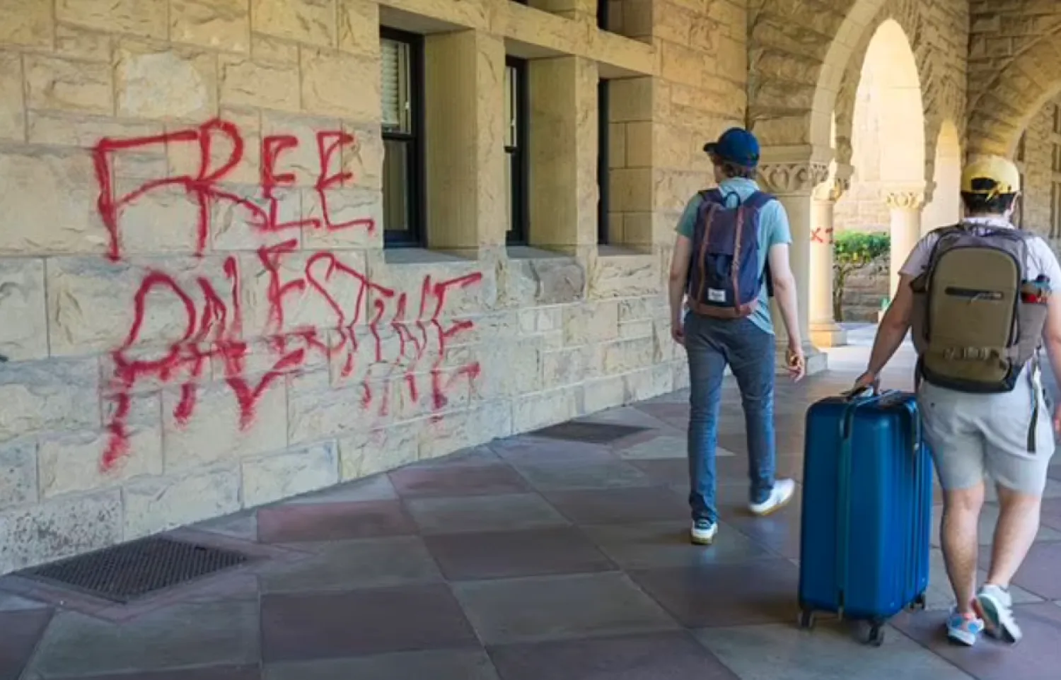 Students walk by graffiti near university president Richard Saller's office at Stanford University in Palo Alto, Calif., Wednesday, June 5, 2024. Stanford University said 13 people were arrested as law enforcement removed pro-Palestinian demonstrators who occupied a campus building early Wednesday that houses the university president and provost offices, with the school saying there was extensive damage inside and outside the building and an officer was lightly injured. (AP Photo/Nic Coury)

