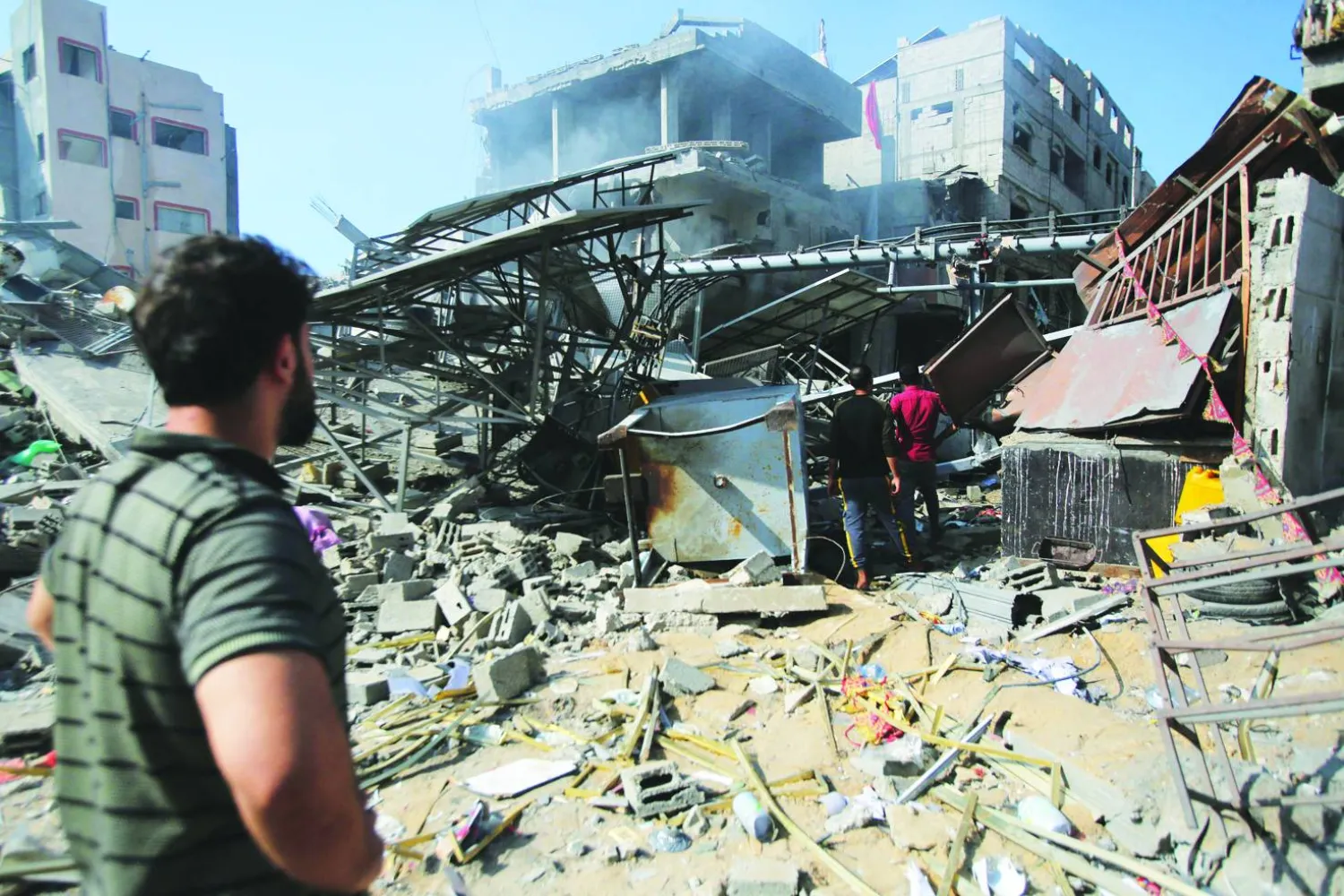 فلسطينيون يتفقدون الأضرار في مخيم الشاطئ للاجئين بمدينة غزة بعد قصف إسرائيلي (أرشيفية - أ.ف.ب)