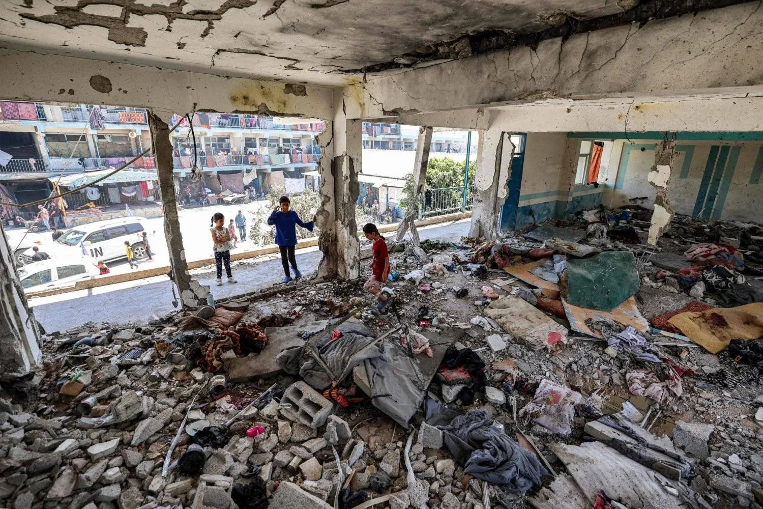 Children inspect a destroyed classroom in a school in the Nuseirat camp for displaced persons in the central Gaza Strip, which was destroyed by an Israeli bombing (AFP)