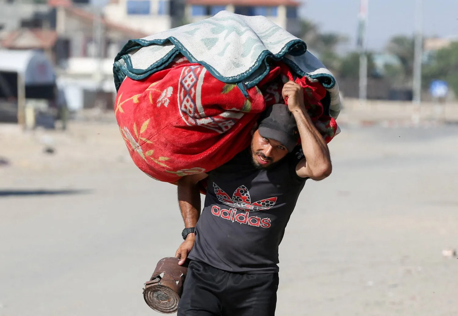 A Palestinian carries his belongings as he flees Rafah due to an Israeli military operation, amid the Israel-Hamas conflict, in Rafah, in the southern Gaza Strip, June 7, 2024. REUTERS/Hatem Khaled