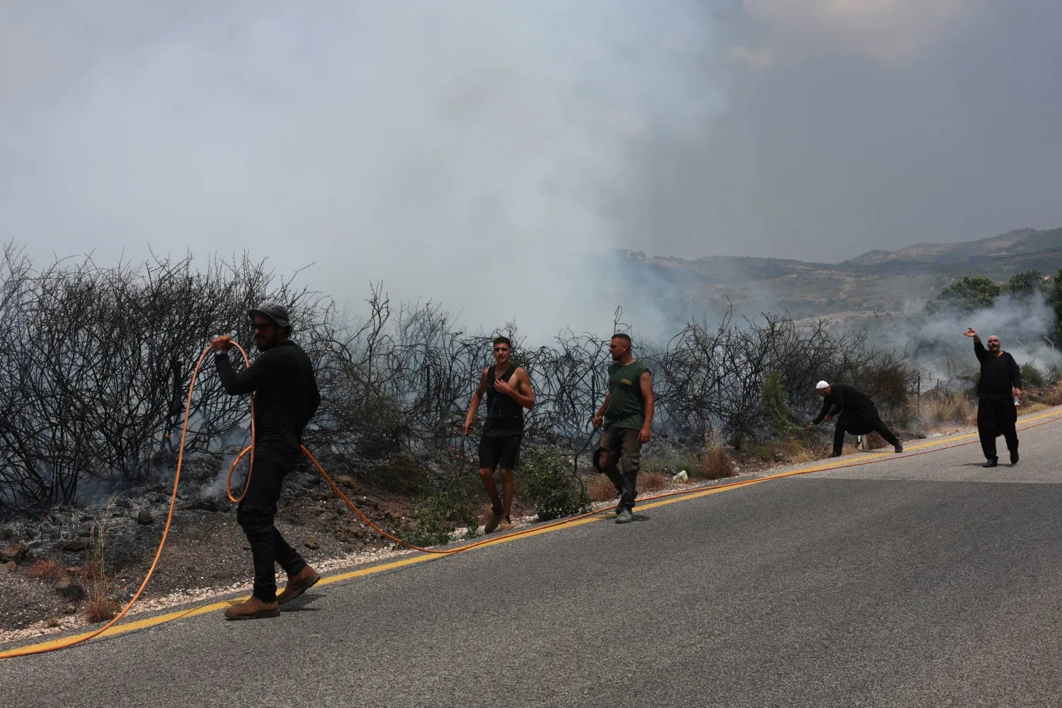 سكان محليون يساعدون رجال الإطفاء في إخماد نيران اشتعلت في الجولان جراء صواريخ «حزب الله» (إ.ب.أ)