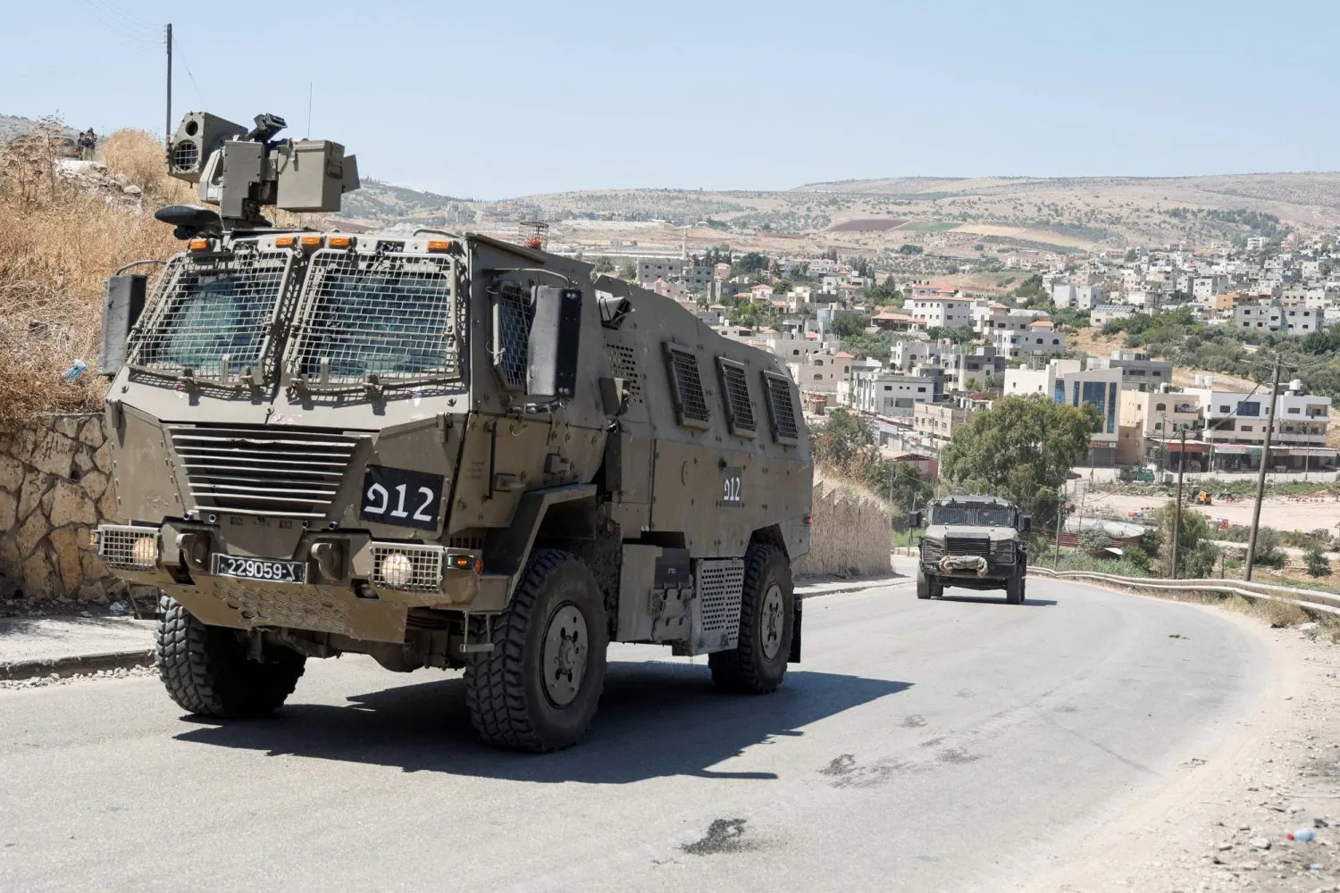 10 Haziran 2024'te Batı Şeria'daki El-Faria Mülteci Kampı'nın önünden geçen askeri araçlar (Reuters)