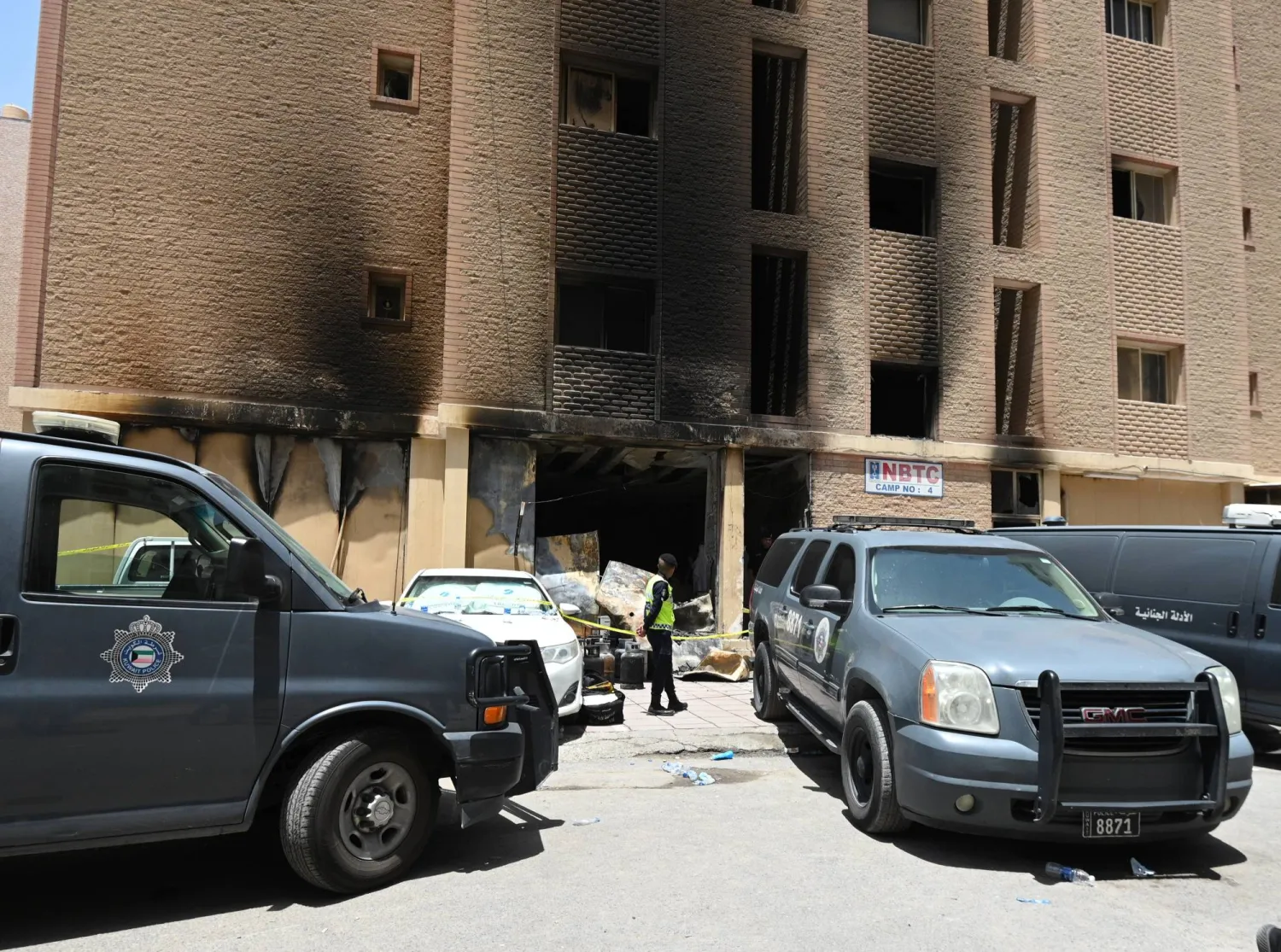 A Kuwaiti policeman stands in front of a residential building after a fire broke out in Mangaf area, southern Ahmadi governorate, Kuwait, 12 June 2024. EPA/NOUFAL IBRAHIM