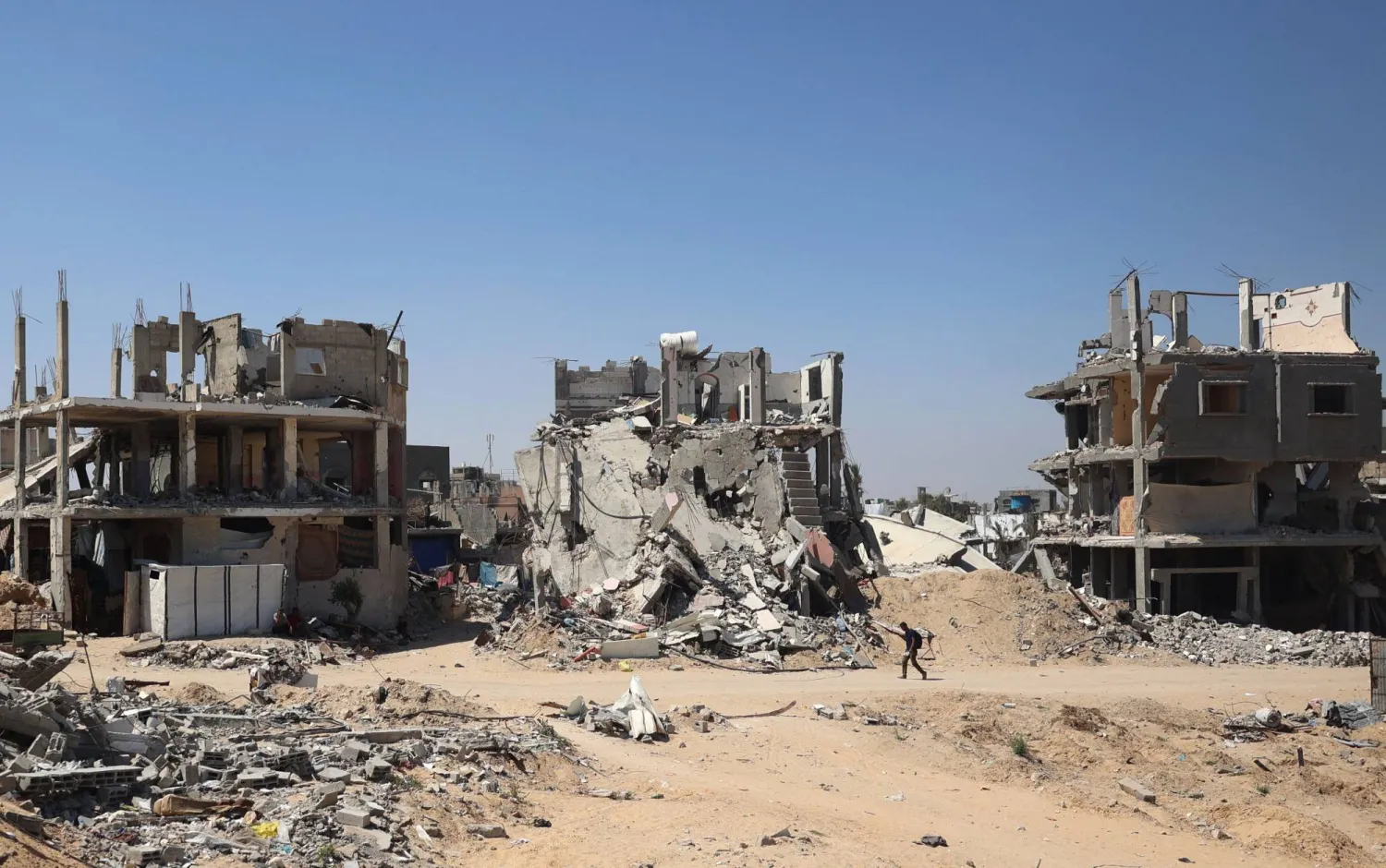 رجل يمشي بجوار المباني المدمرة خلال القصف الإسرائيلي على خان يونس جنوب قطاع غزة في 11 يونيو 2024 (أ.ف.ب)