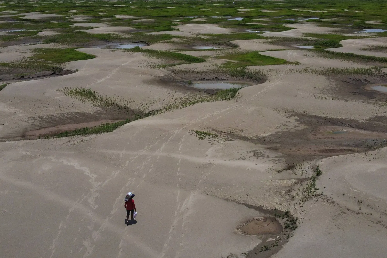 FILE - A resident of a riverside community carries food and containers of drinking water after being distributed due to the ongoing drought in Careiro da Varzea, Amazonas state, Brazil, Oct. 24, 2023. (AP Photo /Edmar Barros, File)