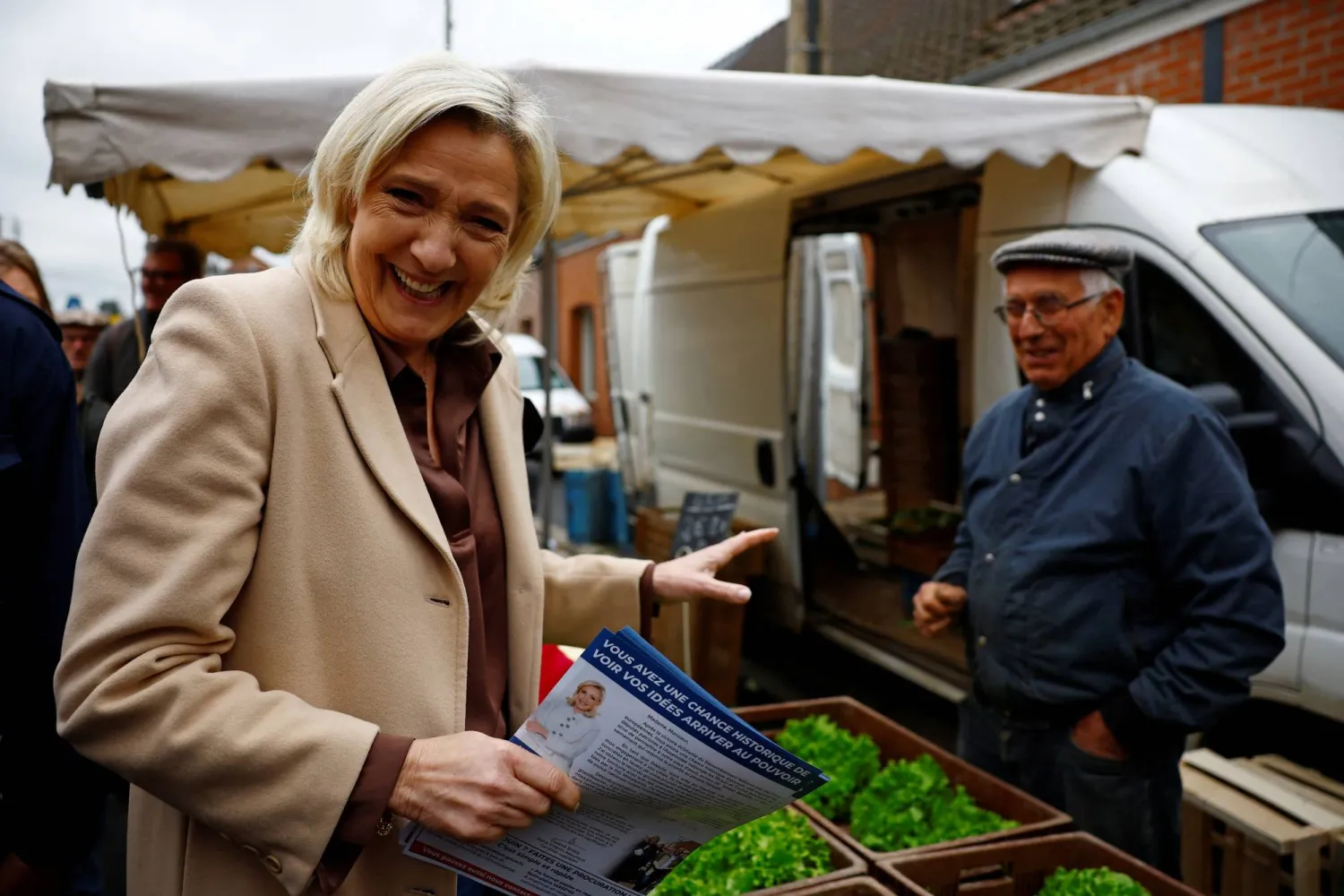 مارين لوبان توزع منشورات أثناء حملتها الانتخابية بسوق في هينان بومونت شمال فرنسا (رويترز)
