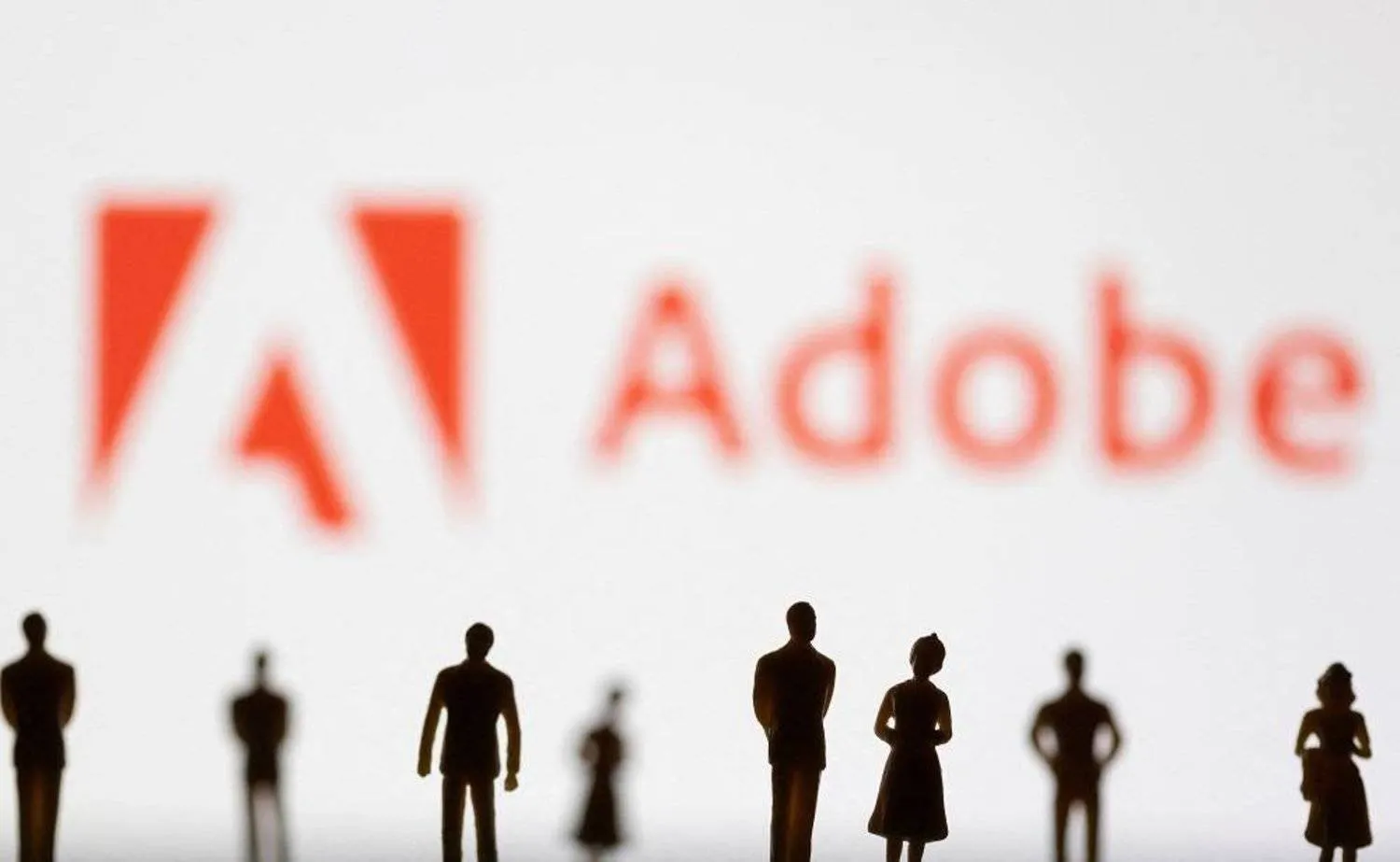 Figurines are seen in front of the Adobe logo in this illustration taken June 13, 2022. (Reuters)
