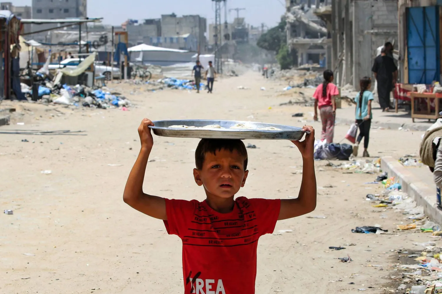 طفل فلسطيني يحمل فوق رأسه صينية تحتوي الخبز في قطاع غزة (أ.ف.ب)