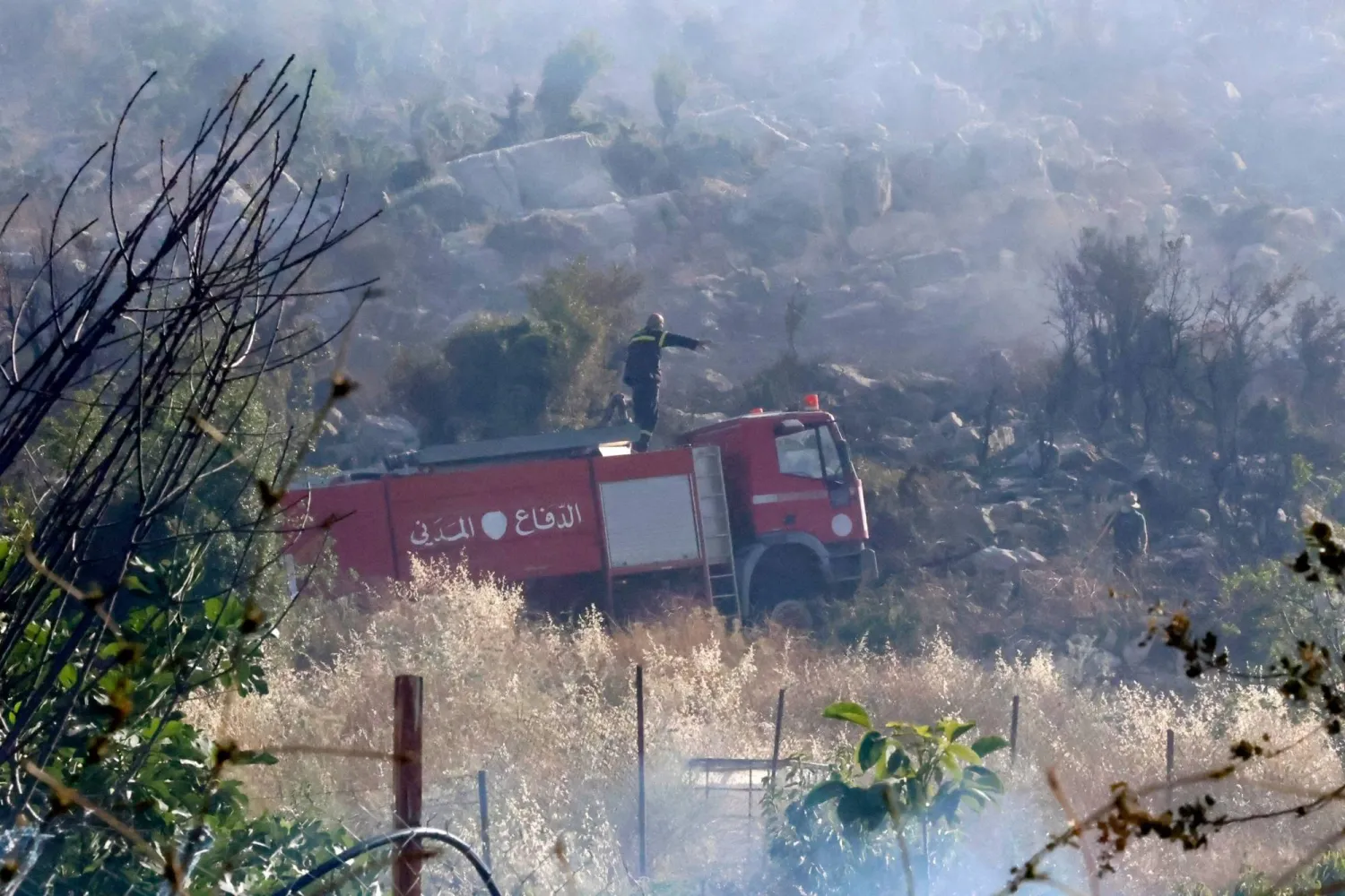 عناصر الإطفاء في الدفاع المدني اللبناني يخمدون حريقاً ناجماً عن القصف الإسرائيلي وأدى لاندلاع حرائق وصلت إلى المنازل في قرية شبعا القريبة من الحدود الجنوبية (أ.ف.ب)