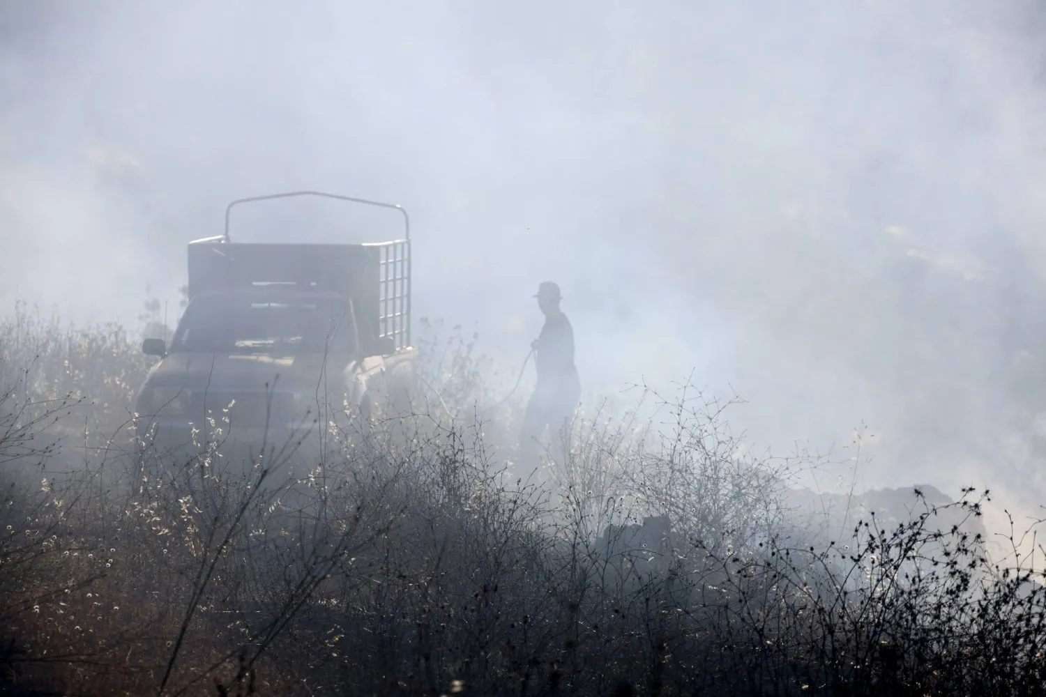 مواطن لبناني يساعد الدفاع المدني على إخماد الحرائق المشتعلة في بلدة شبعا (أ.ف.ب)