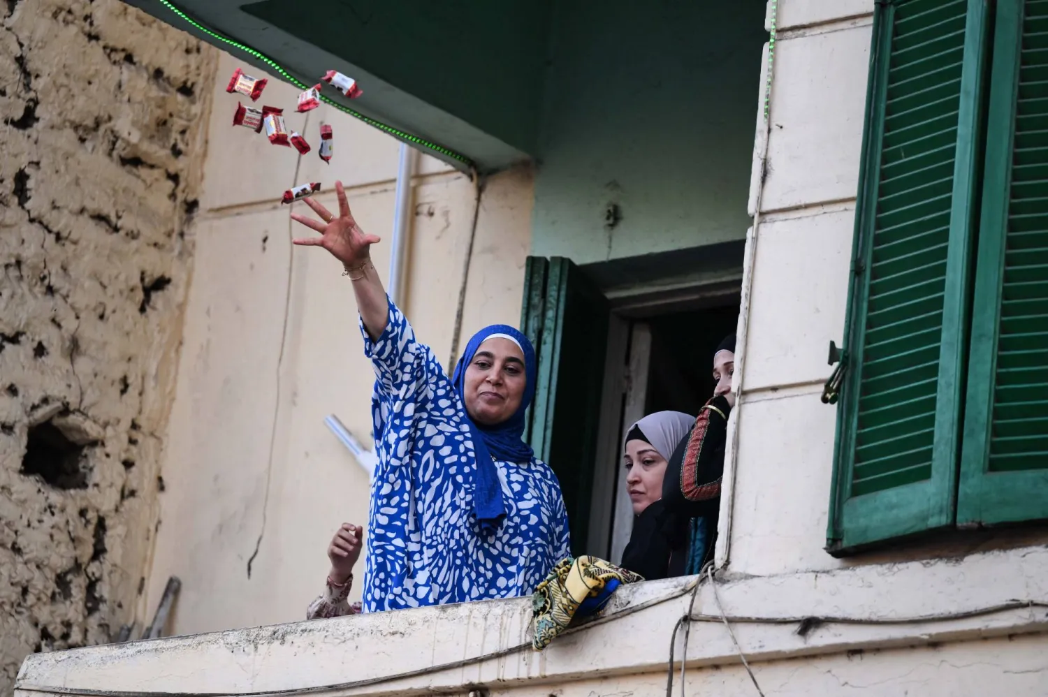 امرأة تلقي الحلوى أثناء صلاة العيد أمام مسجد السيدة زينب في القاهرة (إ.ب.أ)