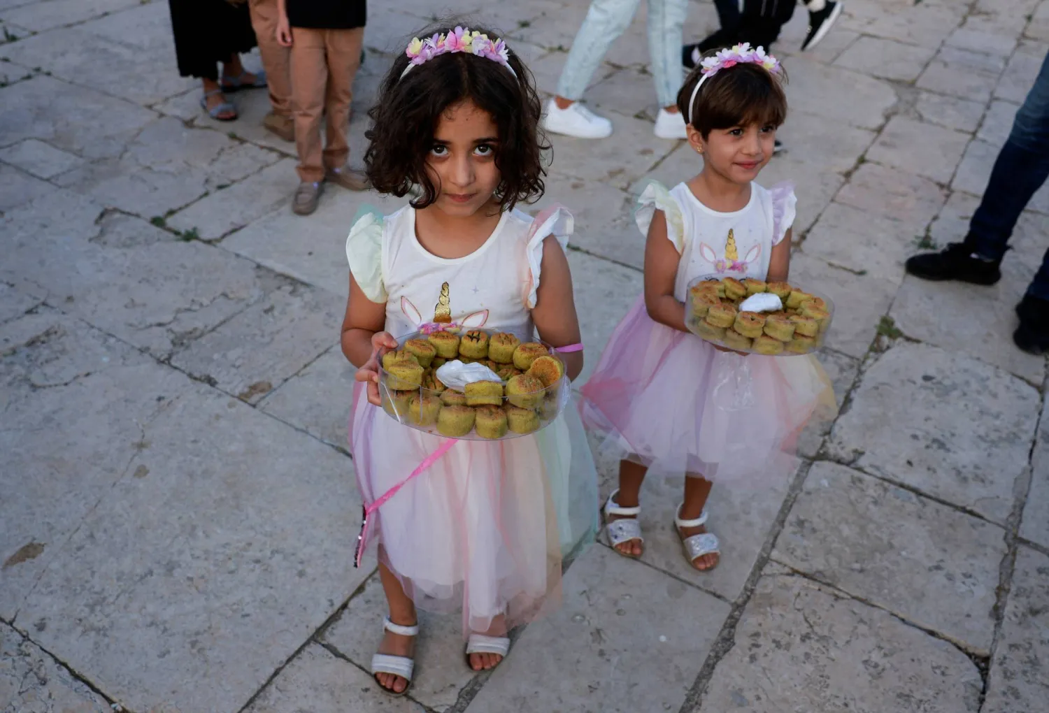 فتيات يحملن صواني من الحلوى لتقديمها للناس بعد صلاة العيد في مجمع الأقصى بالقدس (رويترز)