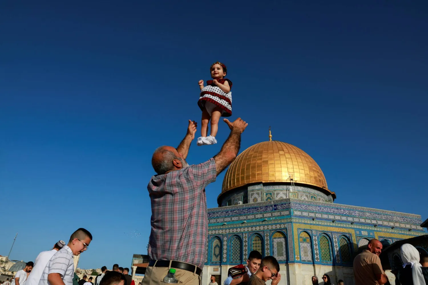 فلسطيني يلاعب طفلته في مجمع الأقصى (رويترز)