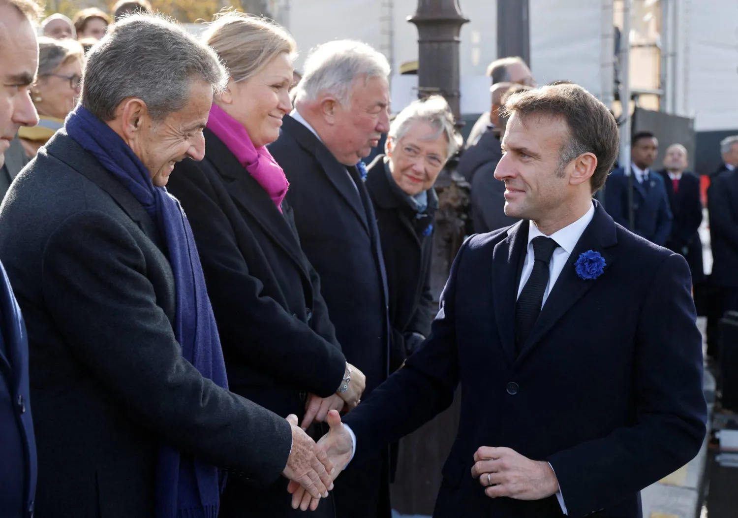 الرئيس الفرنسي الحالي إيمانويل ماكرون يصافح رئيس البلاد الأسبق نيكولا ساركوزي في 11 نوفمبر 2023 (رويترز)